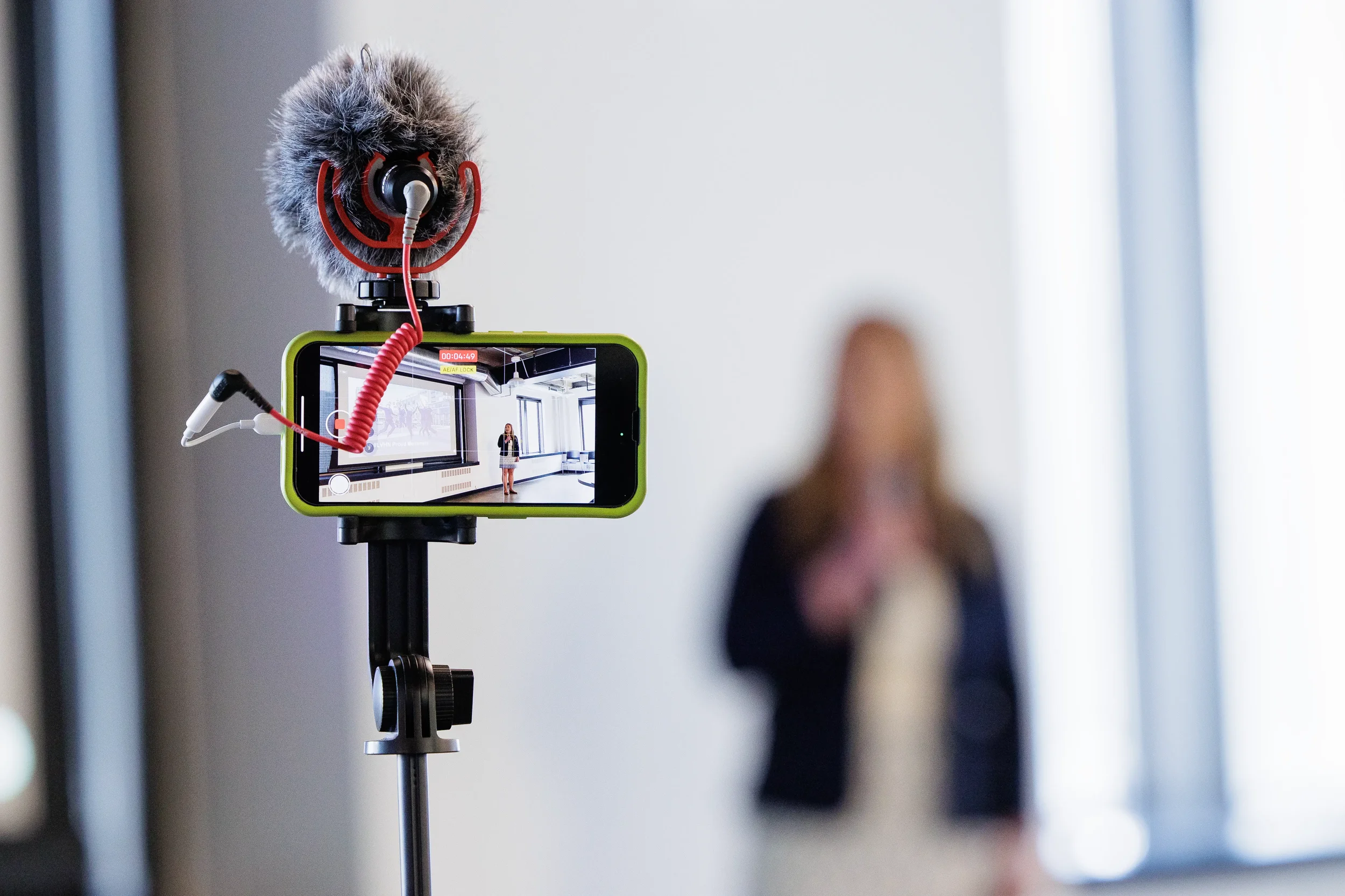 Smartphone on tripod with microphone records a speaker presenting at Orlando corporate event
