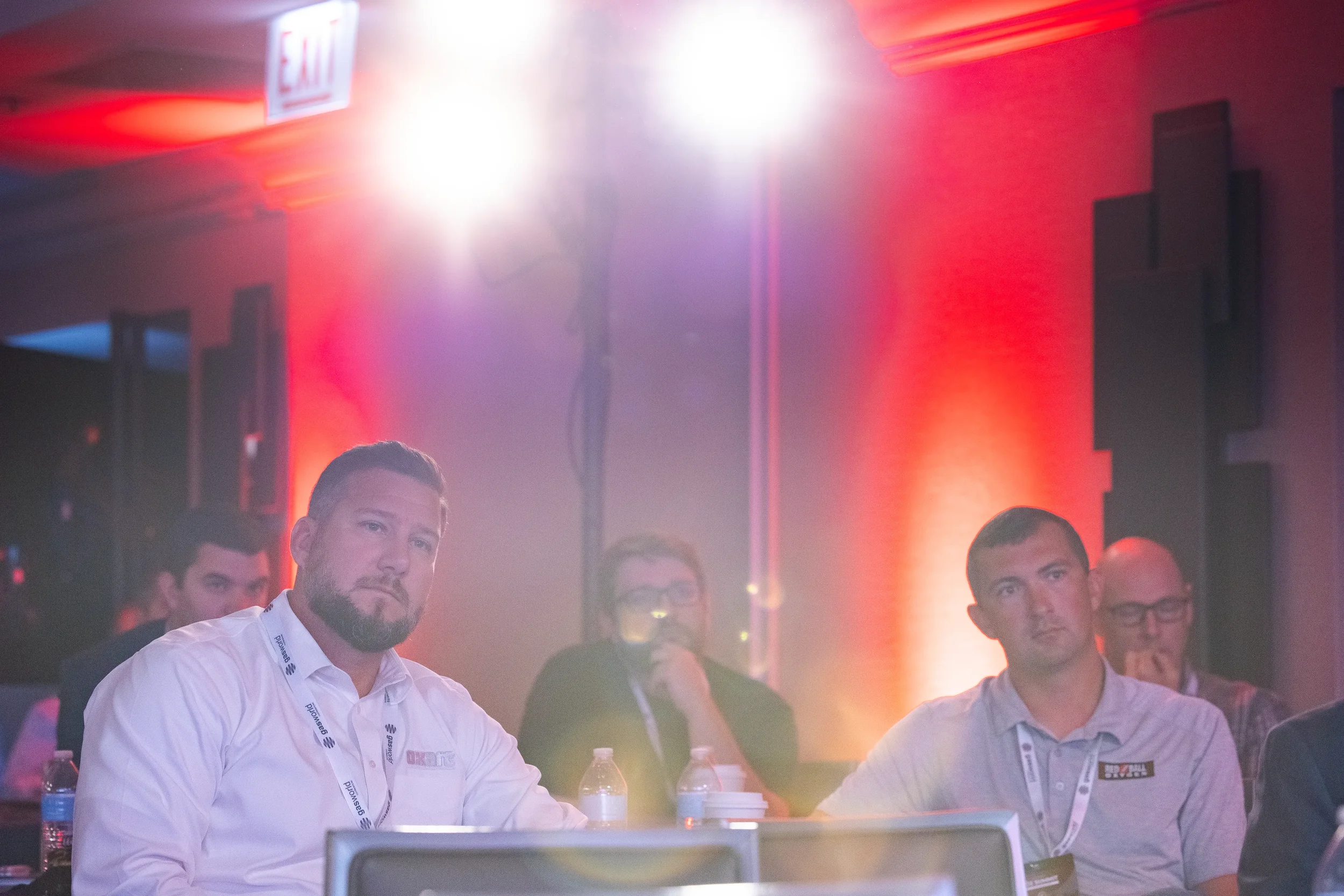 Conference attendees with lanyards watch presentation from seated table at Chicago corporate summit