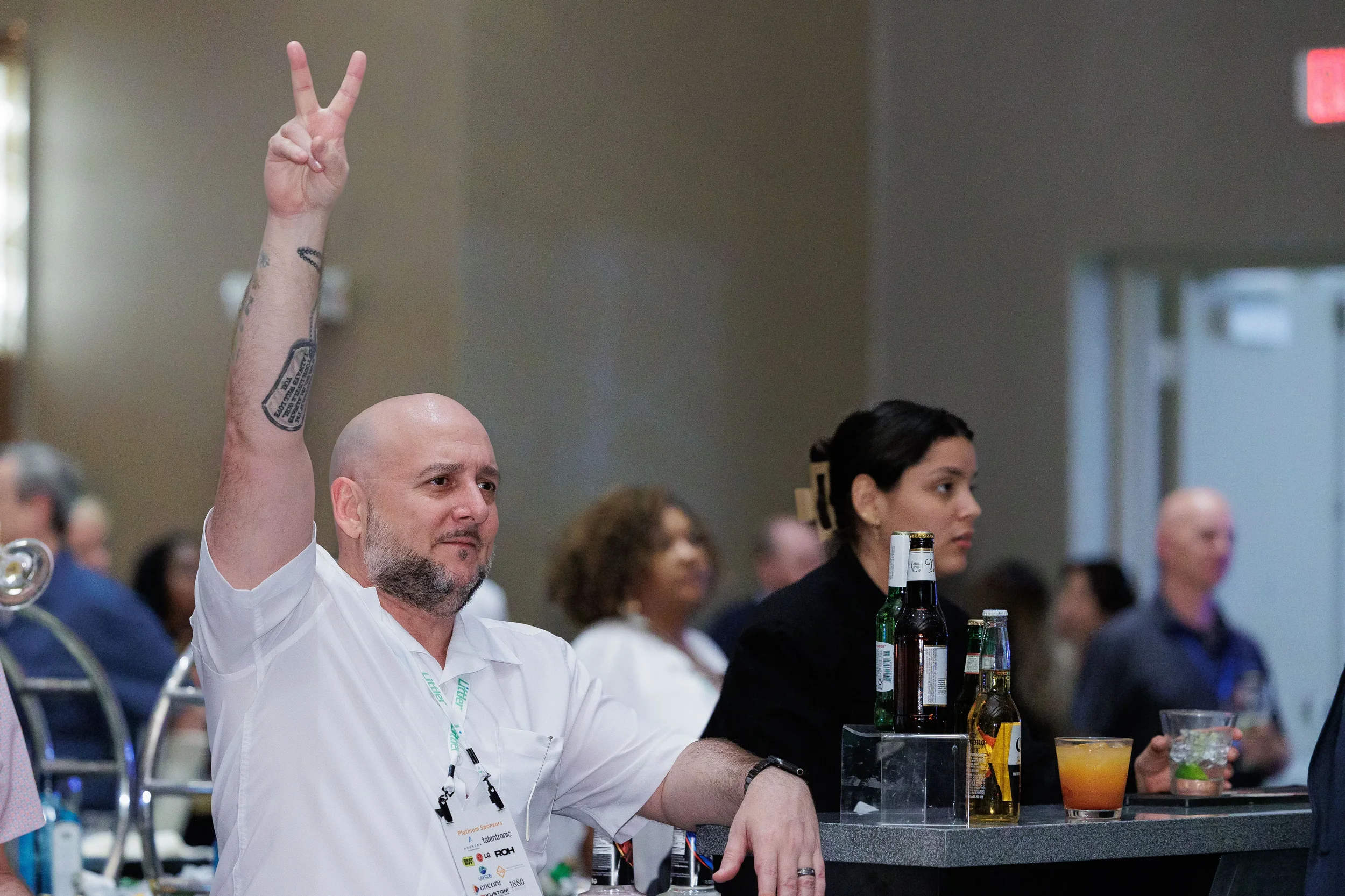Attendee with lanyard flashes peace sign at cocktail bar during Chicago industry conference networking event