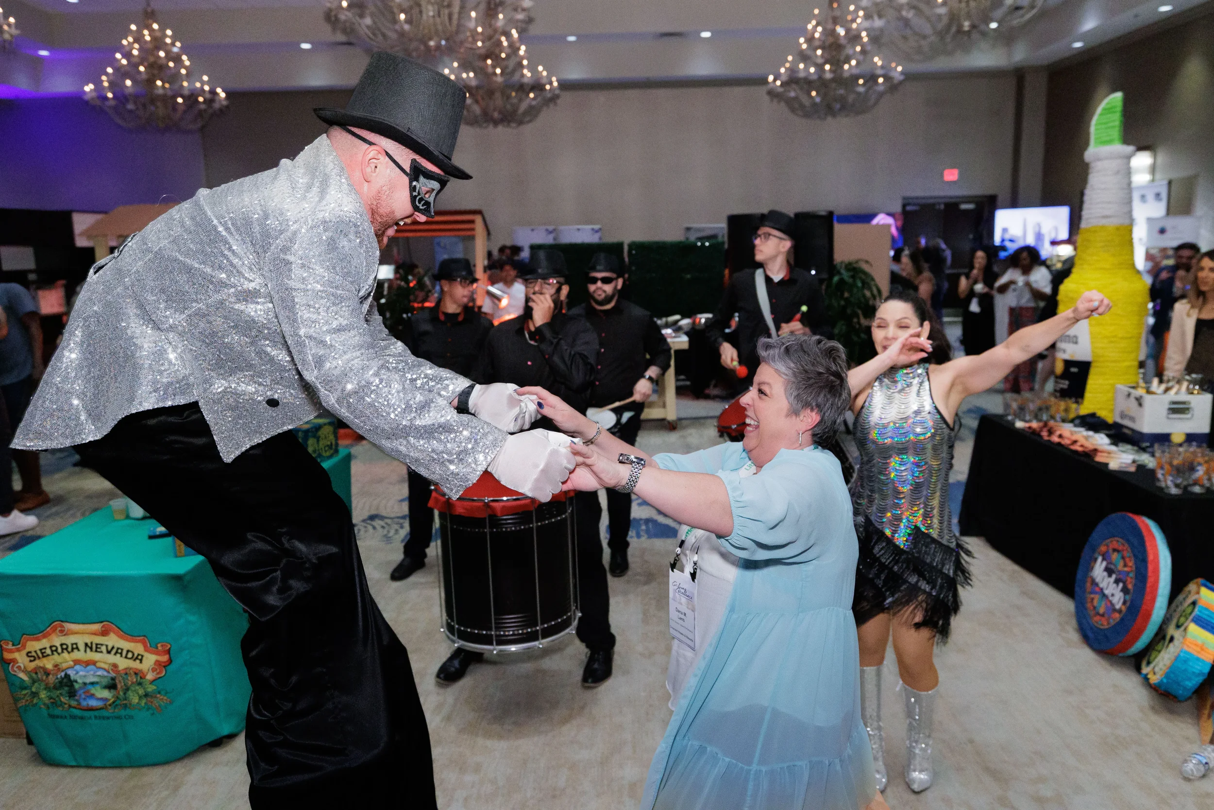 Costumed stilt entertainer dances with laughing attendee in ballroom at Chicago corporate conference gala