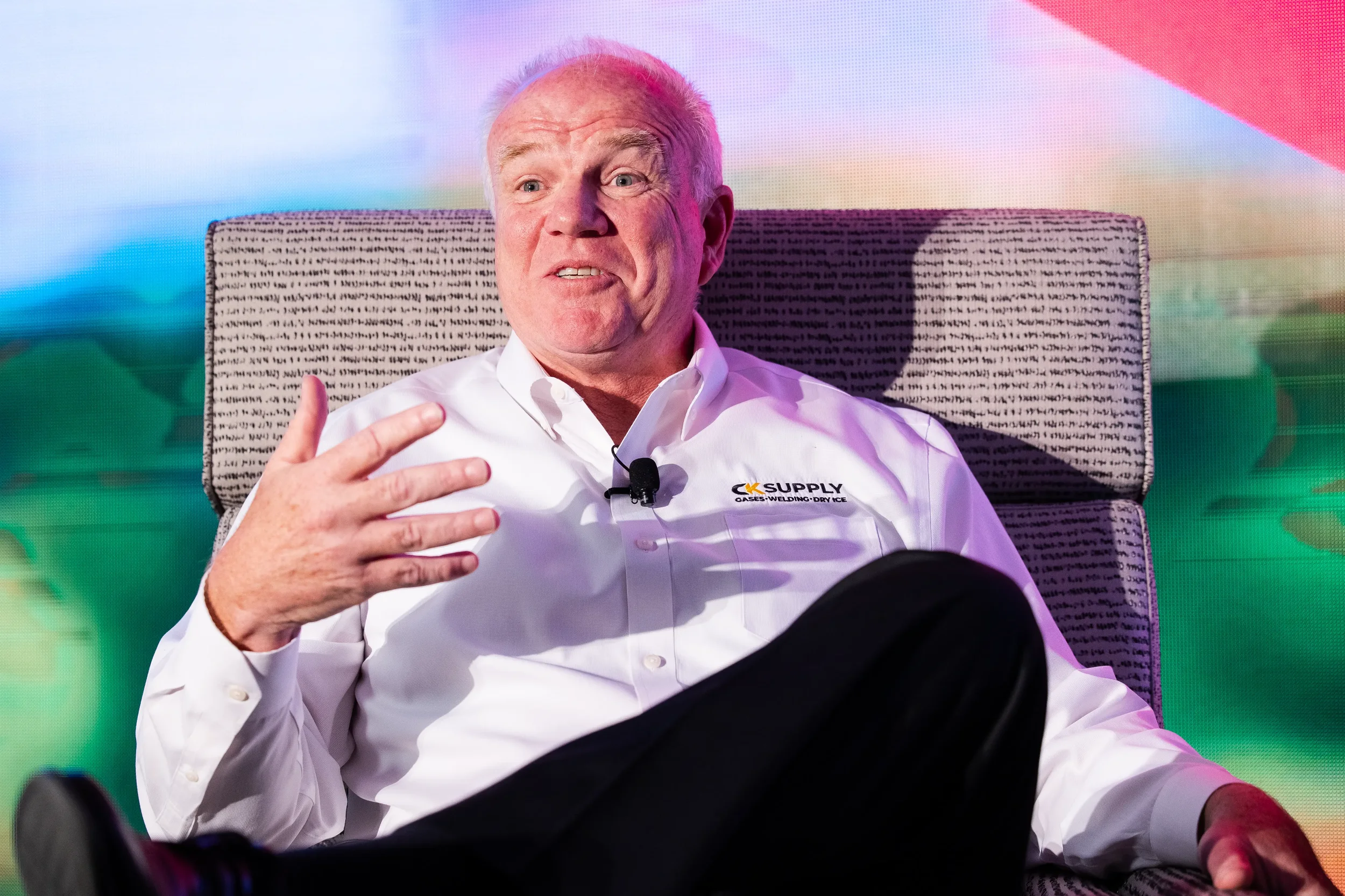 Speaker gestures while seated during interview session at Orlando industry conference event