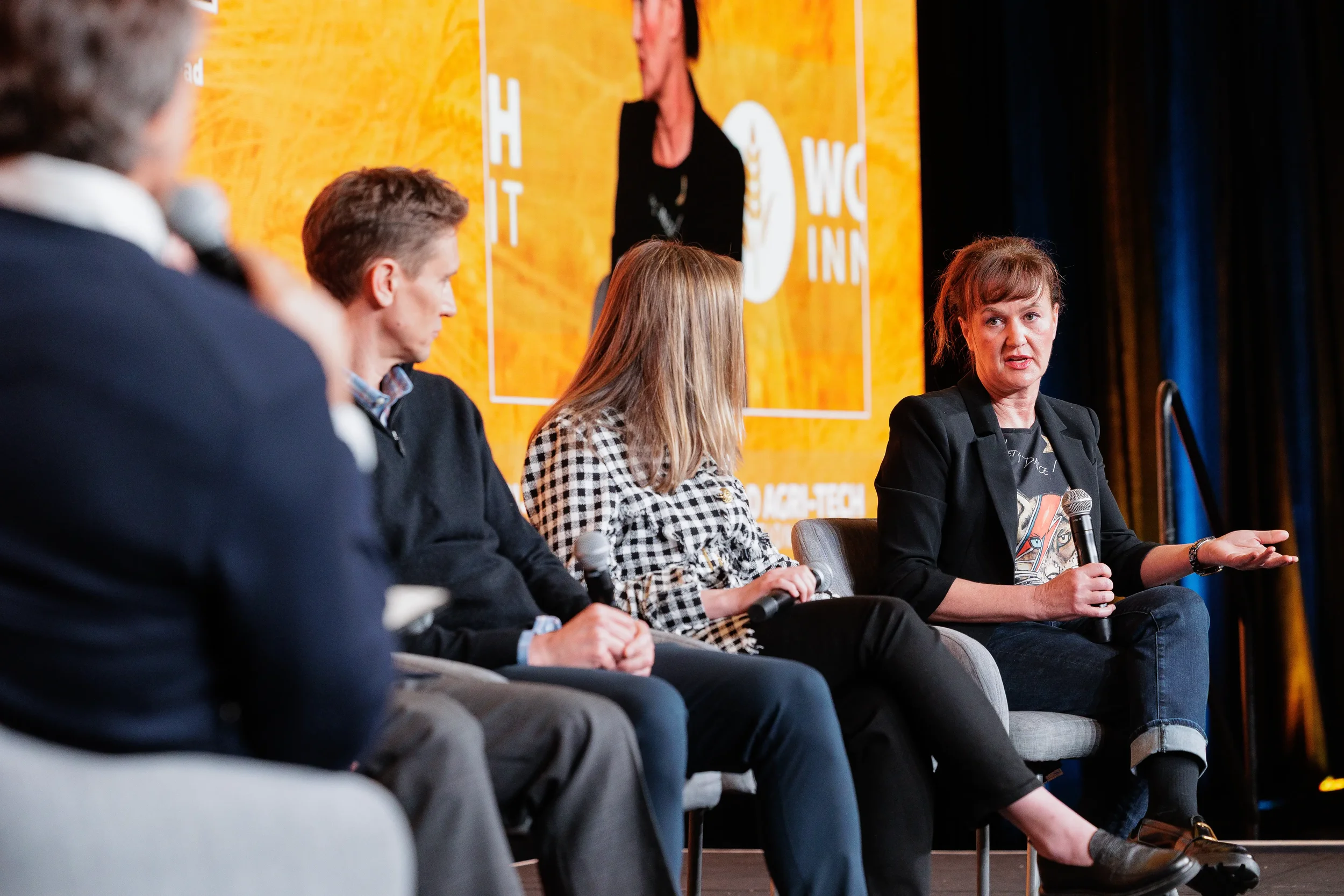 Female panelist gestures while speaking to fellow panelists on stage at Chicago industry conference