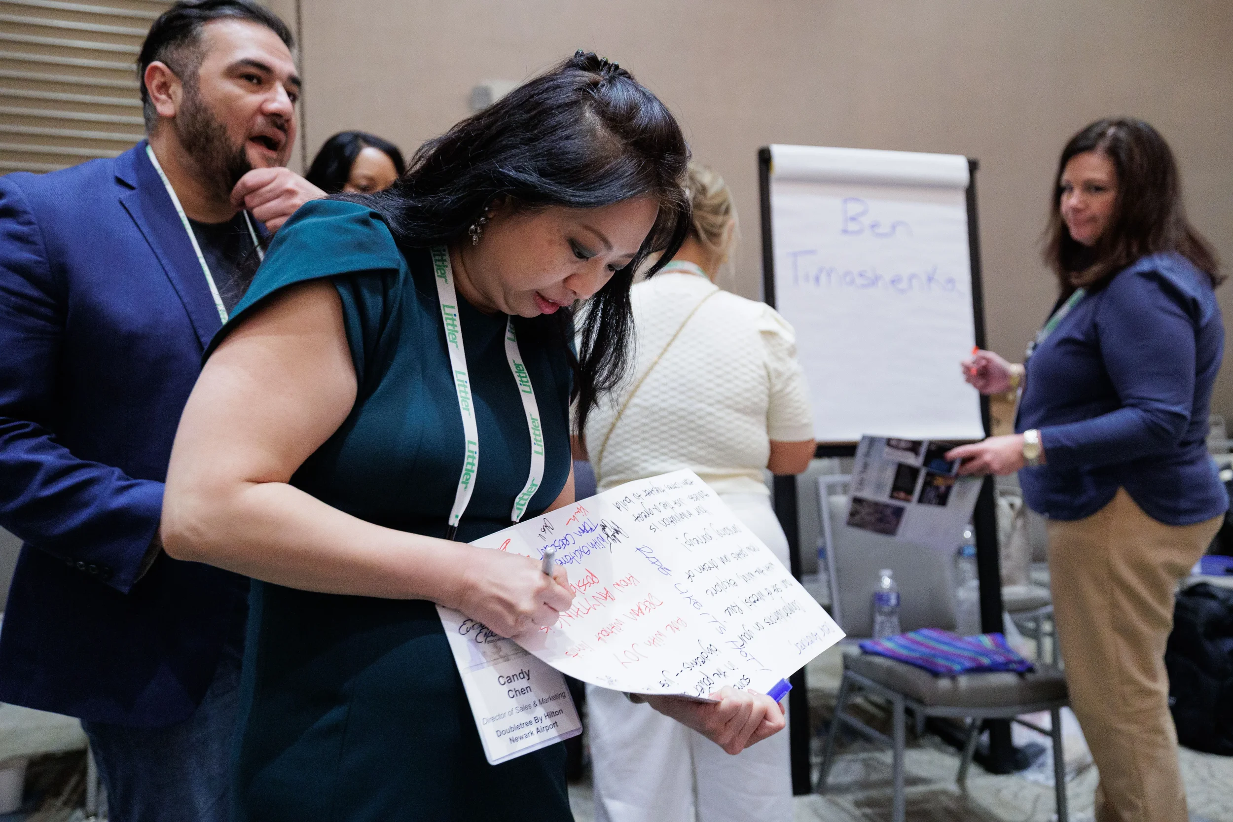 Attendee with lanyard writes notes on large paper during group activity at Orlando industry conference