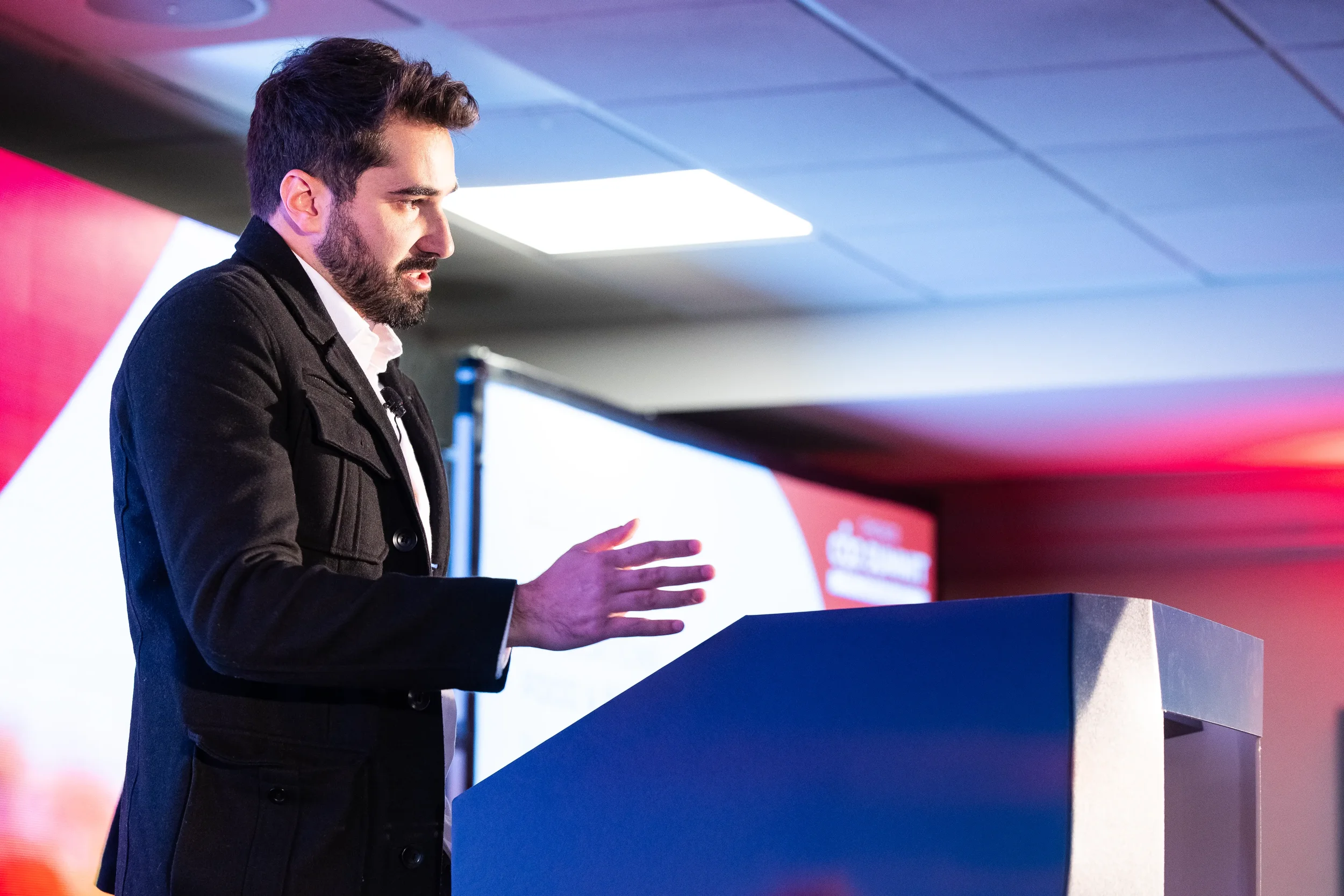 Keynote speaker gestures while presenting from podium on stage at Orlando industry conference