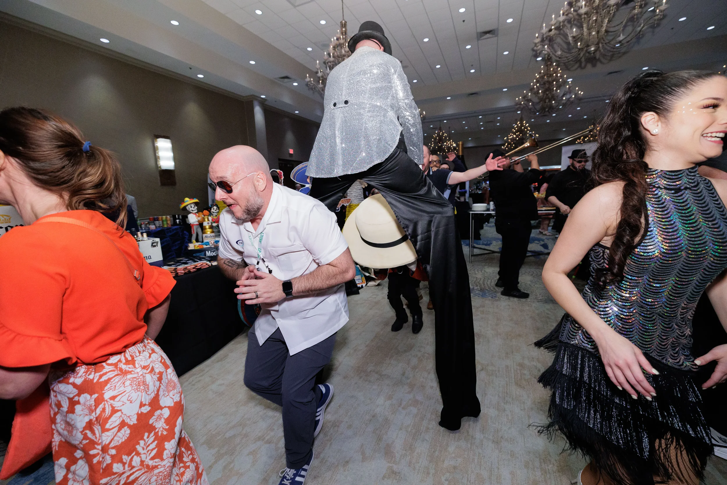 Attendees dance alongside costumed stilt walker and performer in ballroom at Chicago corporate event