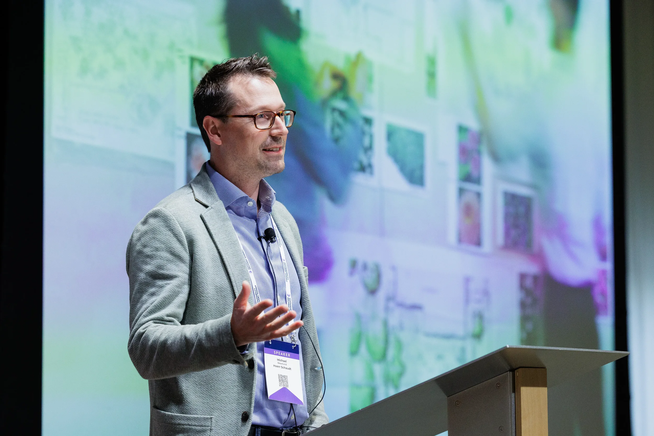 Speaker gestures from podium during presentation with screen behind at Chicago industry conference