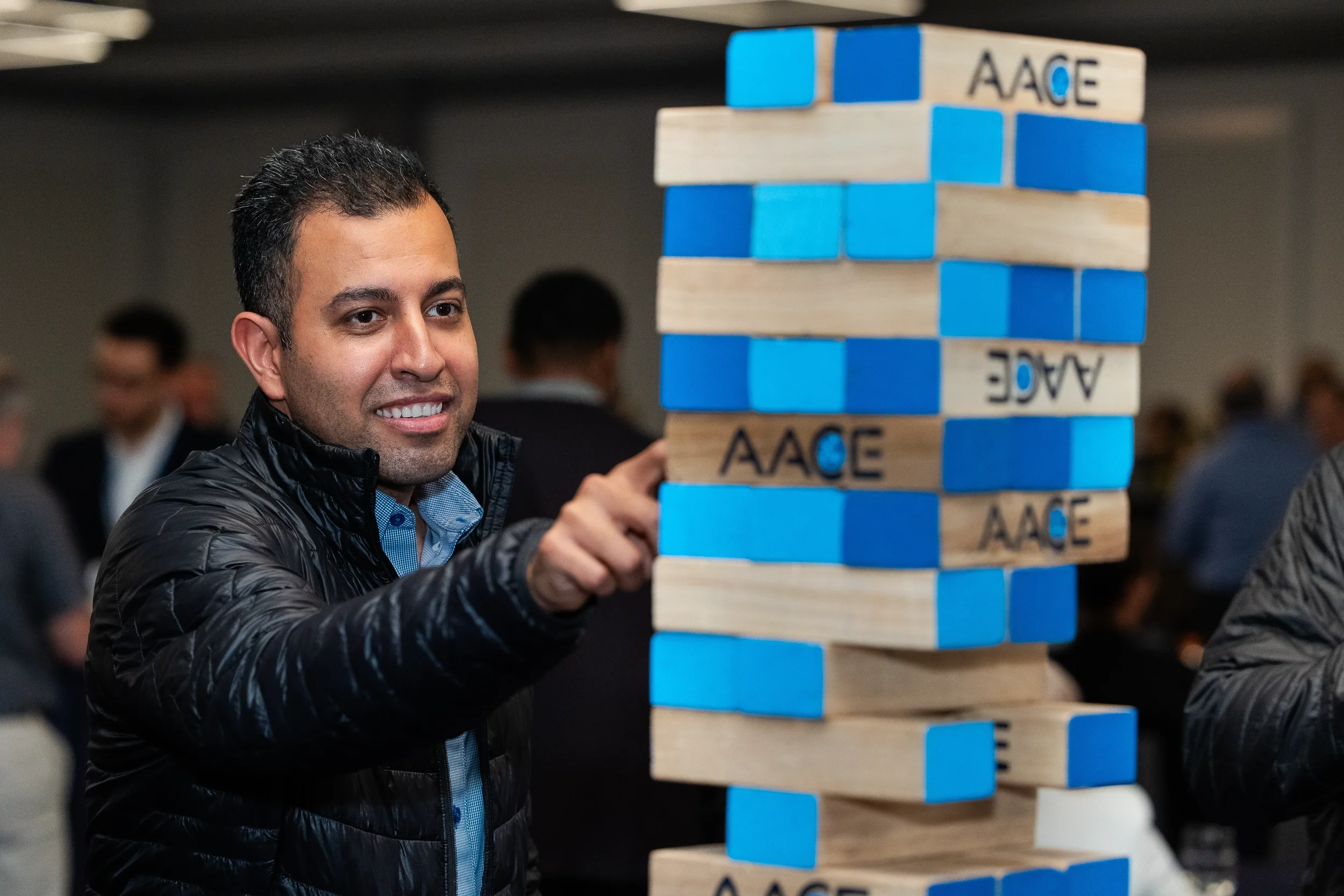 Attendee plays AACE-branded giant Jenga during networking reception at Chicago conference event