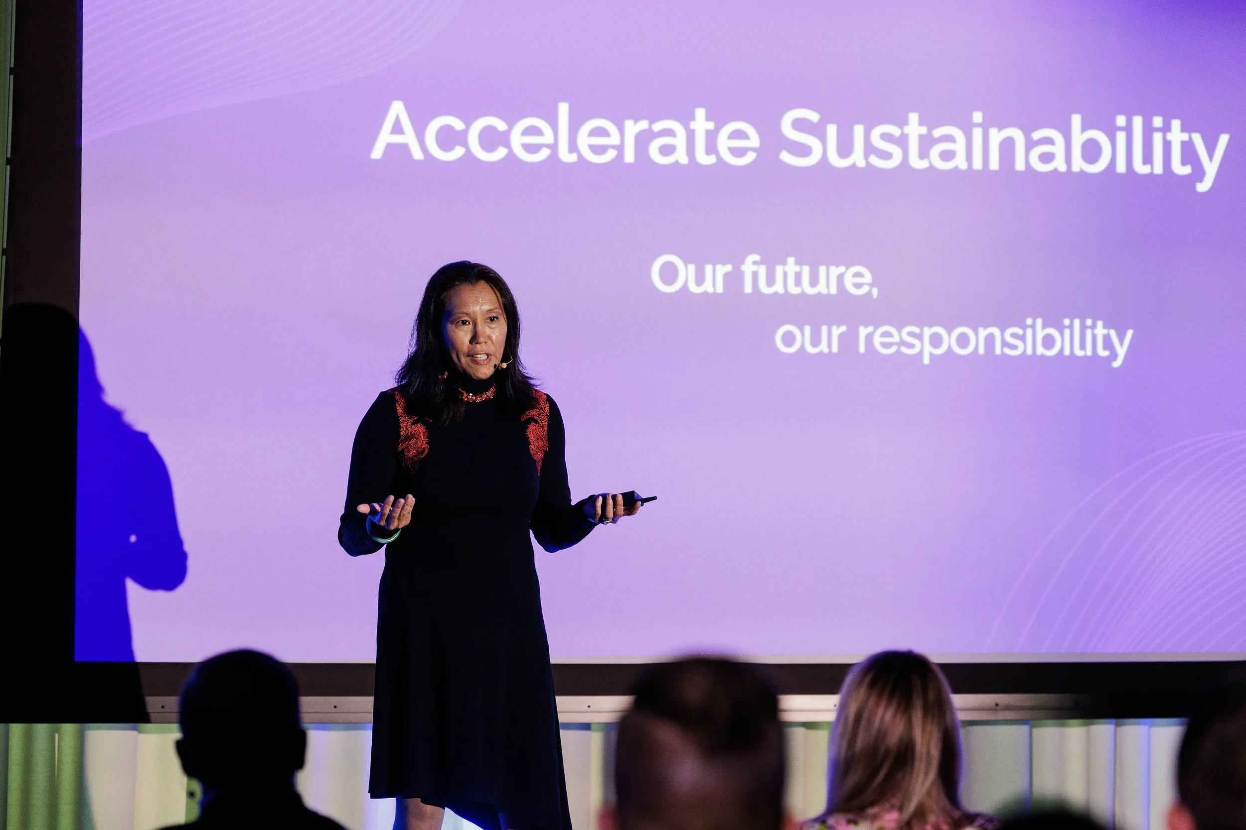 Speaker presents to audience in front of purple projection screen at Orlando industry conference