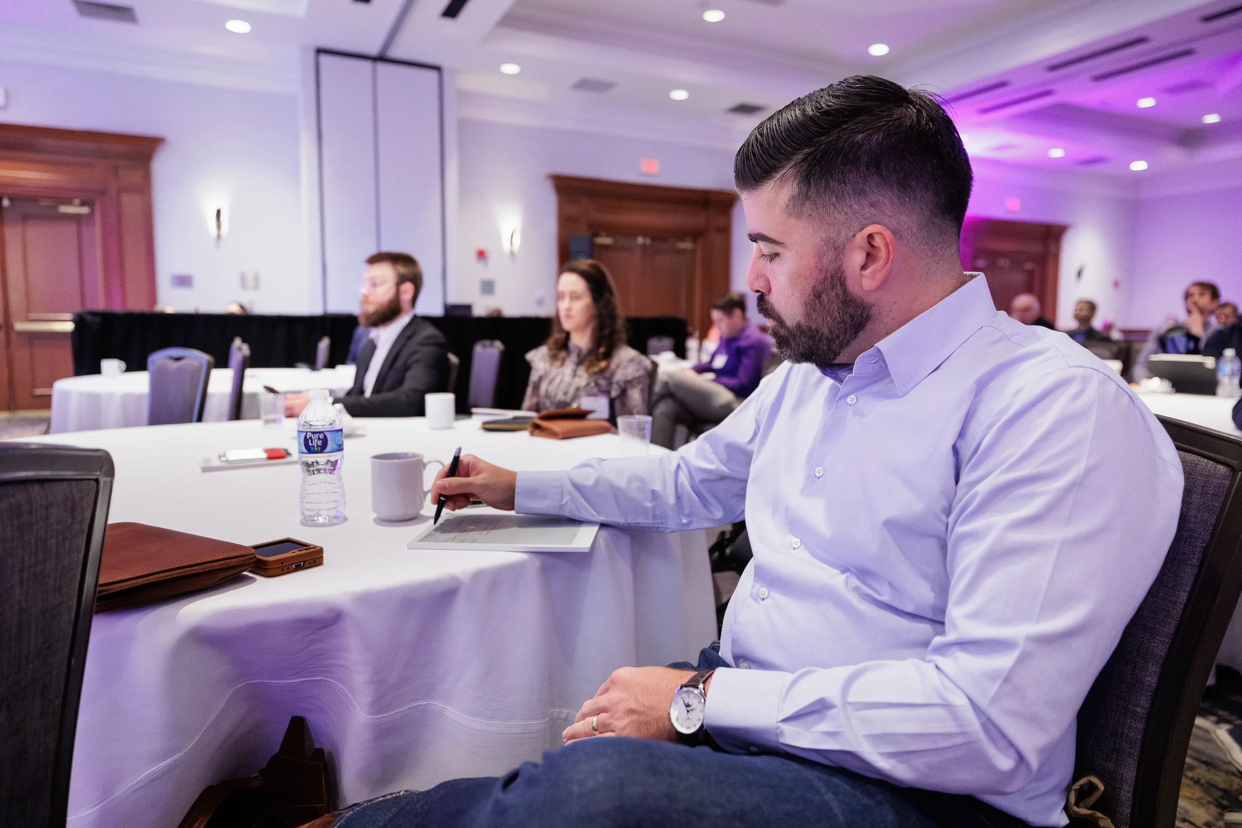 Attendee writes notes during roundtable discussion at Chicago industry conference