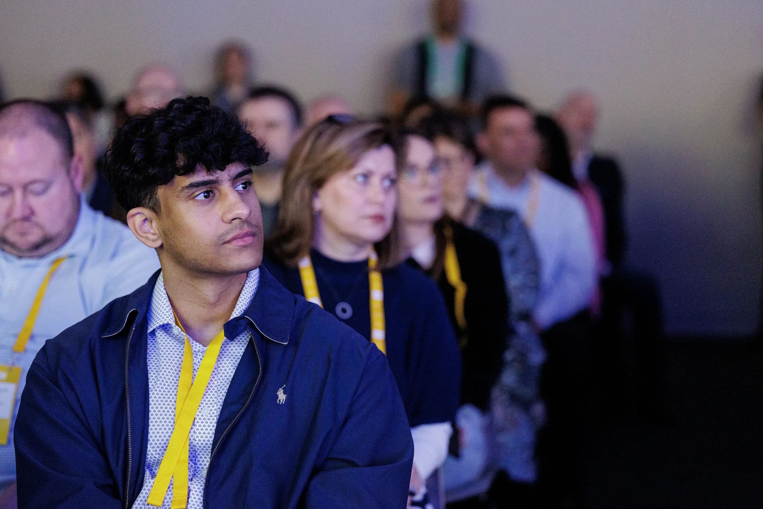 Close-up of attentive attendee with yellow lanyard watching session at Chicago industry conference
