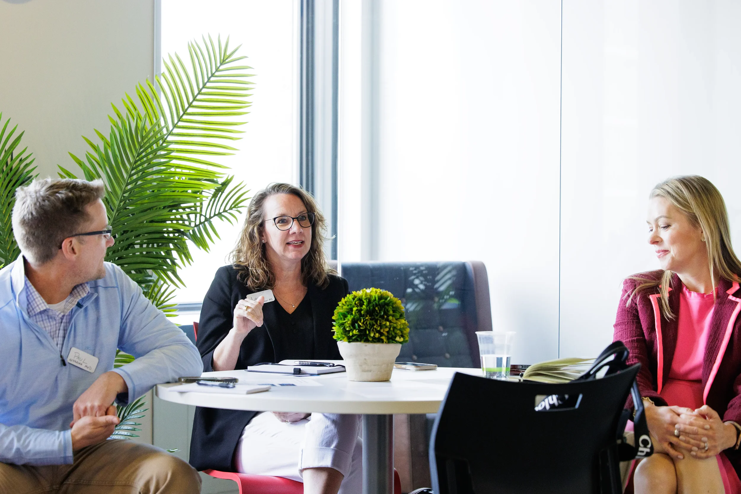 Three attendees converse at a round table with a plant backdrop during Chicago corporate event