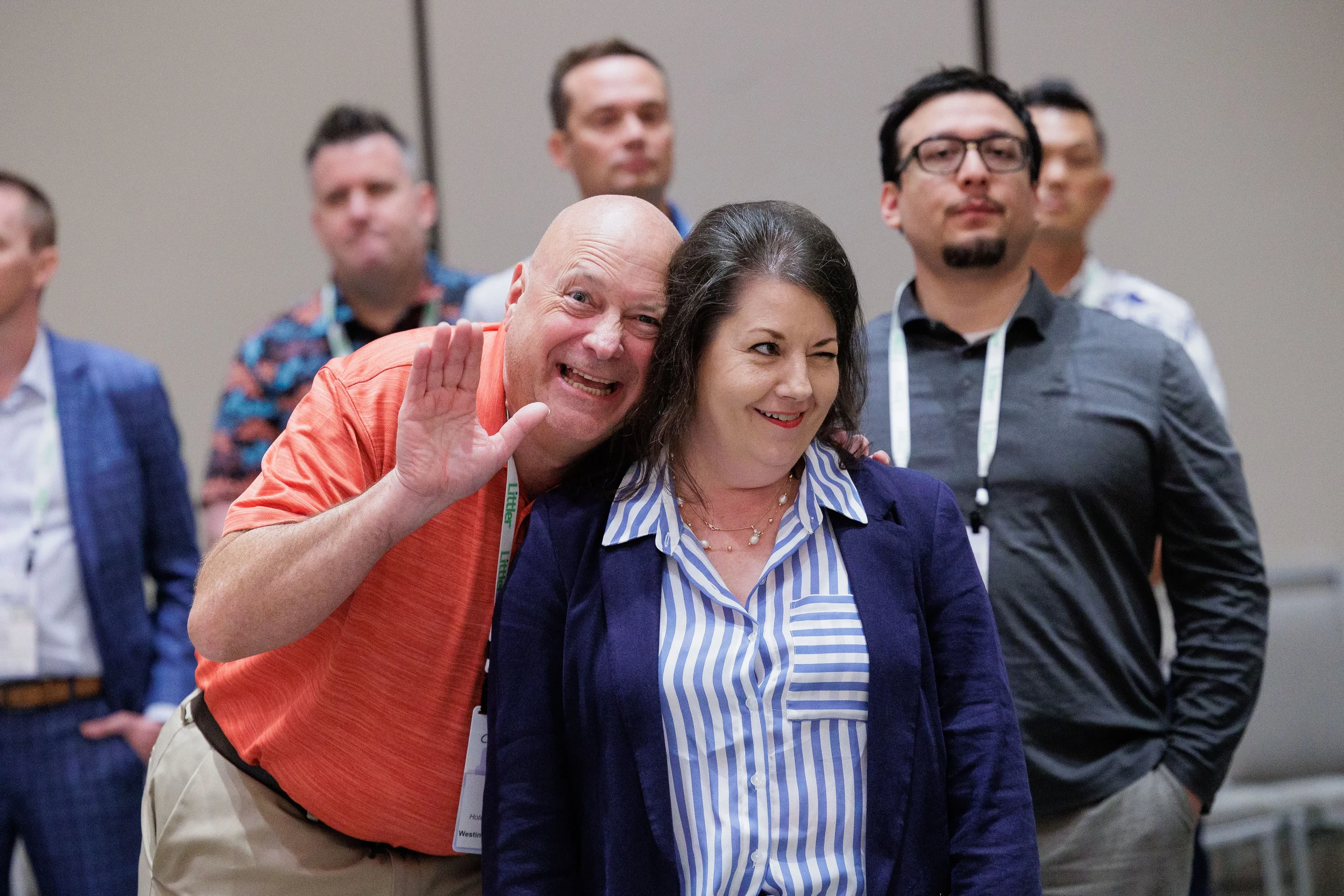 Two attendees with lanyards laugh and pose together during group photo at Chicago industry conference