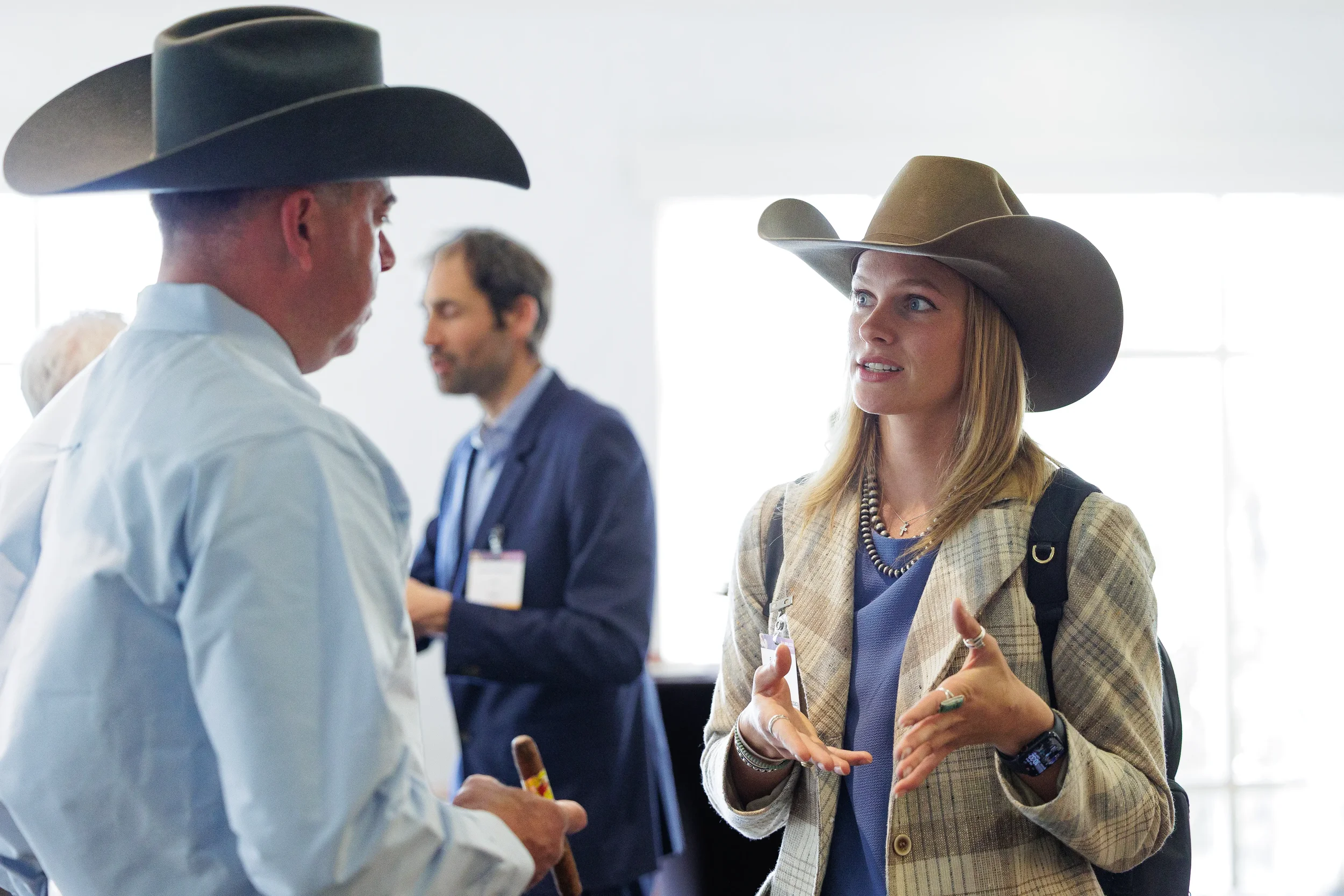 Attendees wearing cowboy hats converse in lobby during Orlando industry conference
