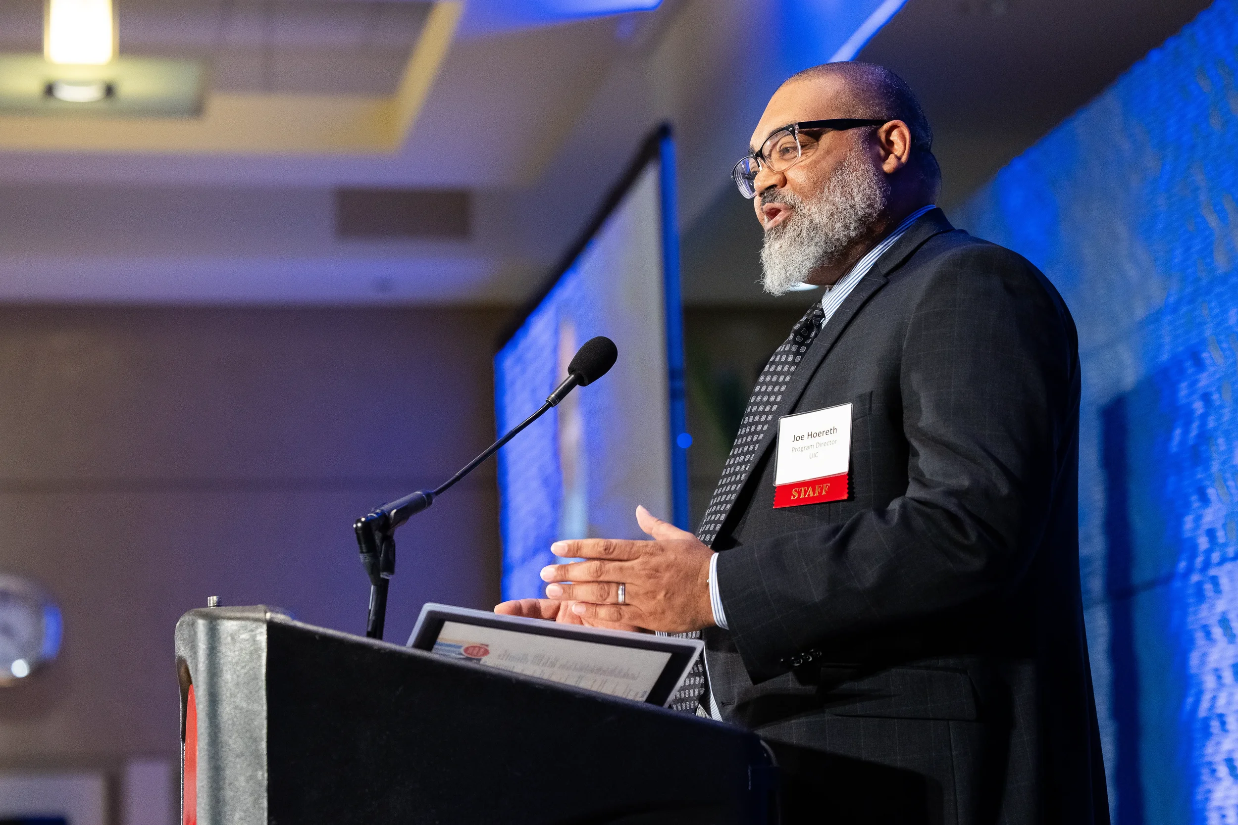 Speaker gestures while addressing audience from podium at Orlando corporate conference