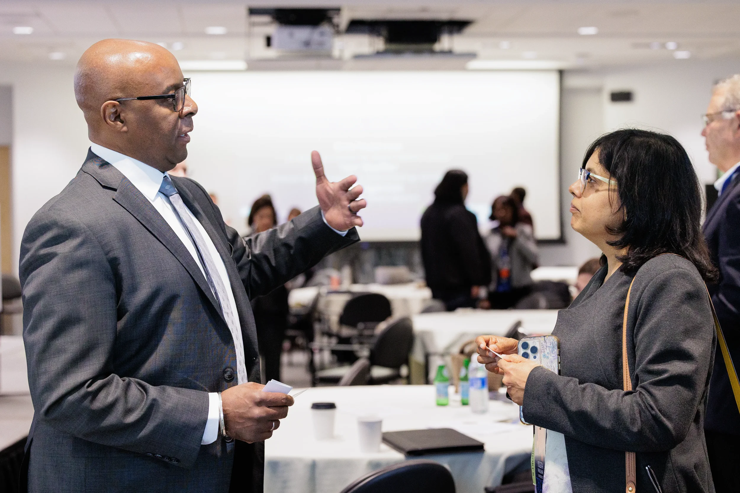 Two attendees exchange business cards and converse during networking break at Chicago industry conference