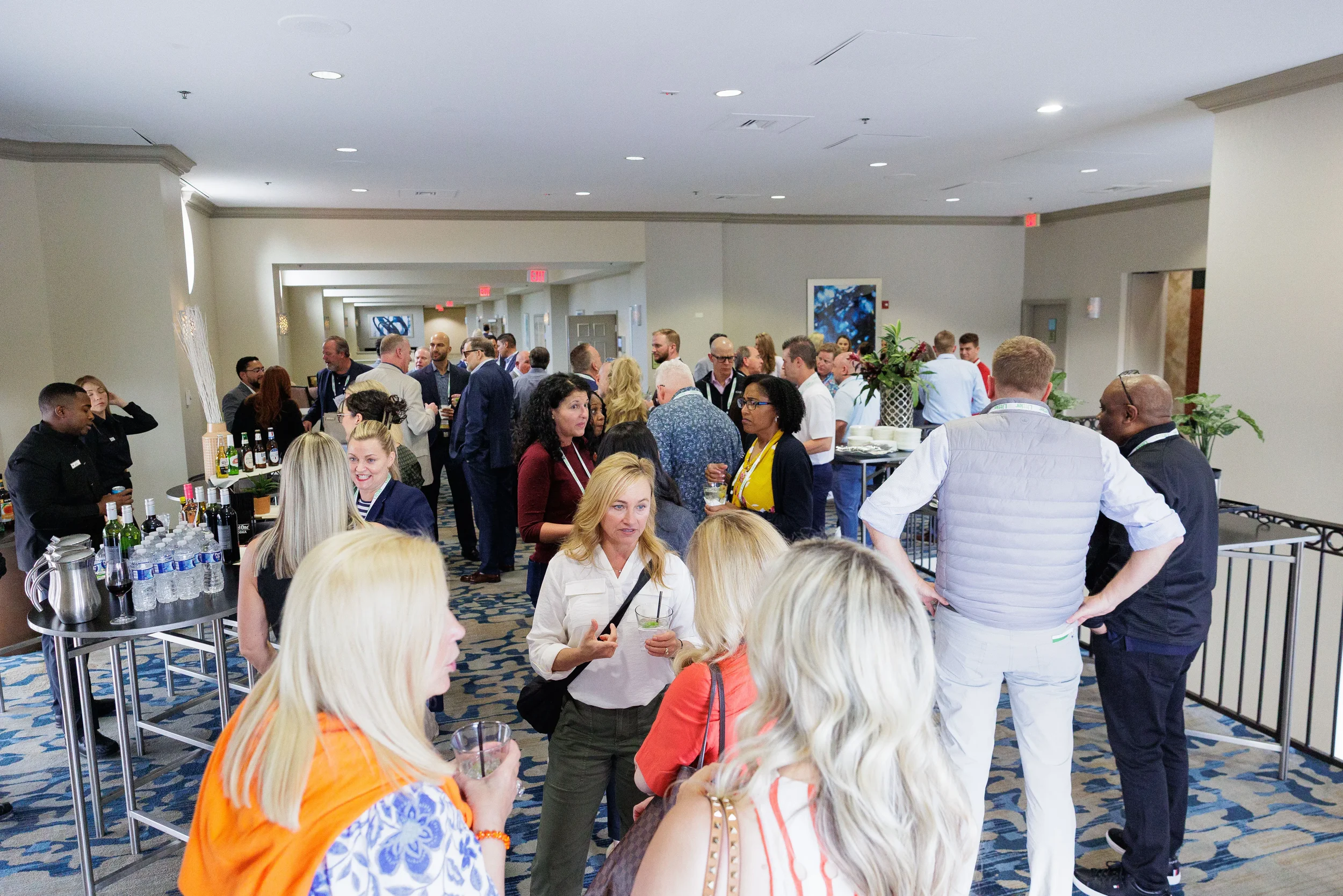 Large group of attendees mingle during cocktail hour networking reception in Orlando corporate conference foyer