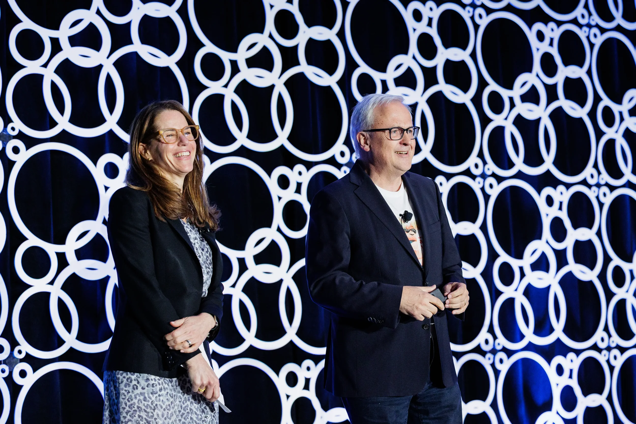 Two speakers present on stage with illuminated circular backdrop at Orlando industry conference