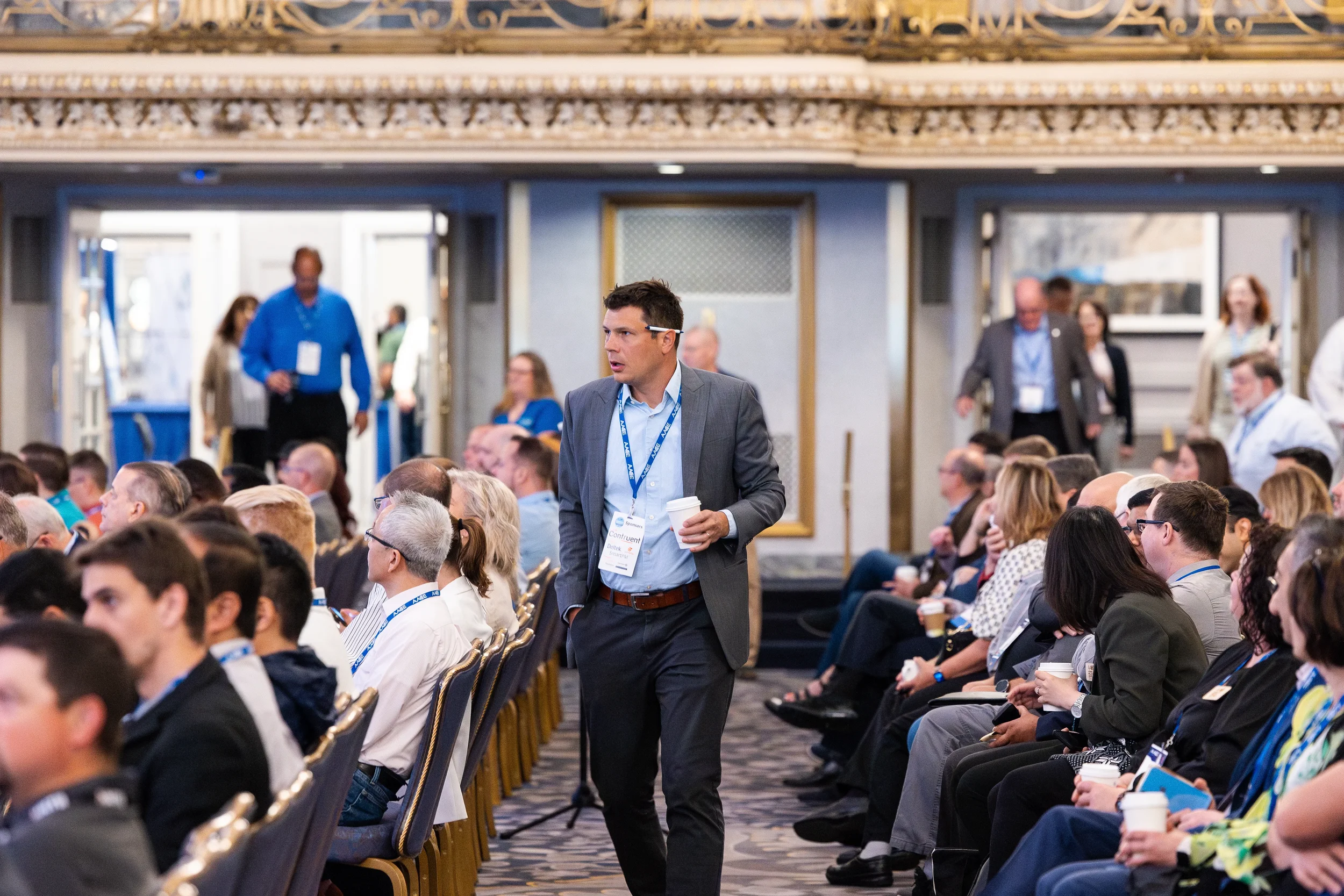 Attendee walks down aisle in ornate ballroom during AACE International conference session in Orlando