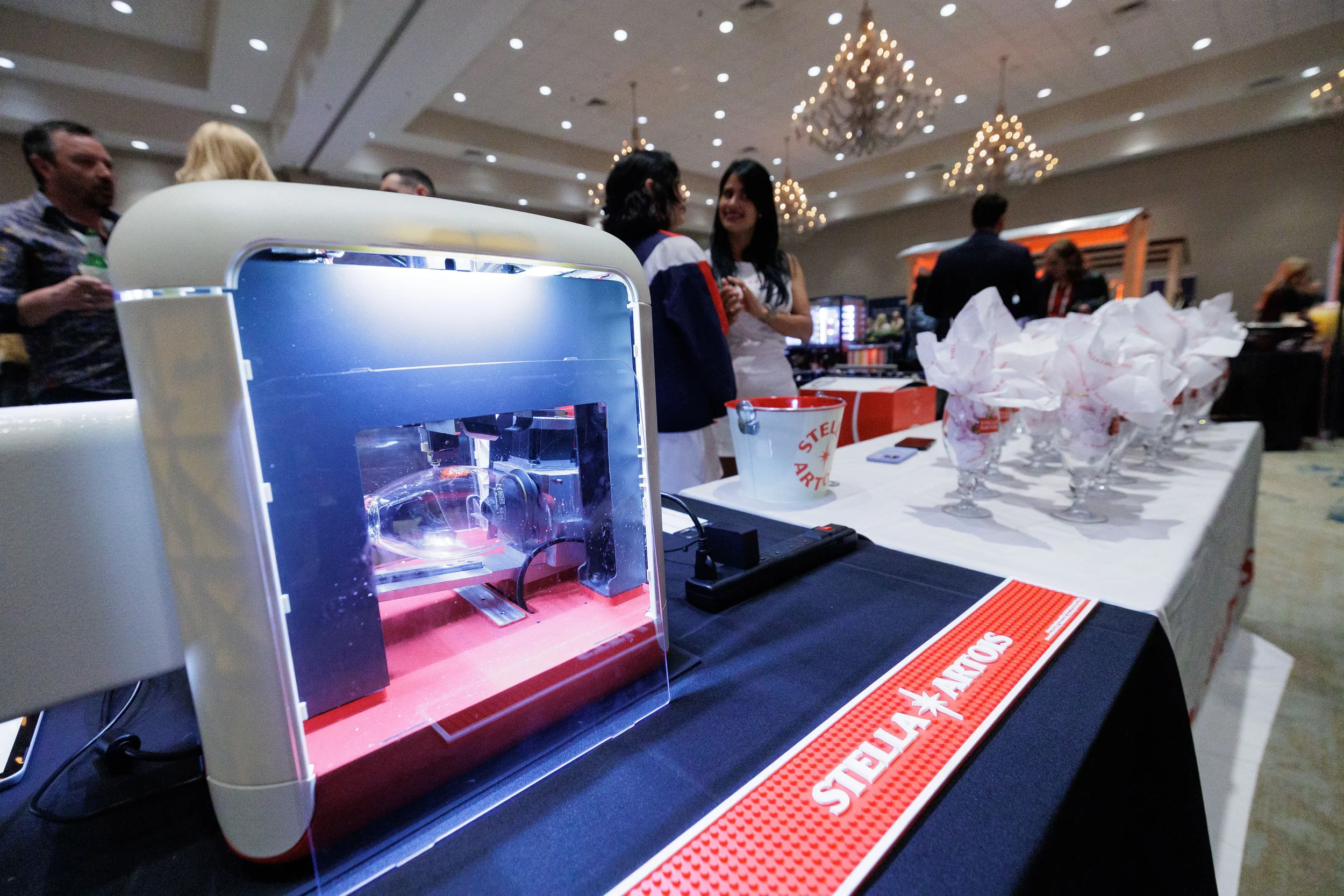 Glassware engraving machine at branded exhibitor booth in chandelier ballroom at Orlando corporate trade show