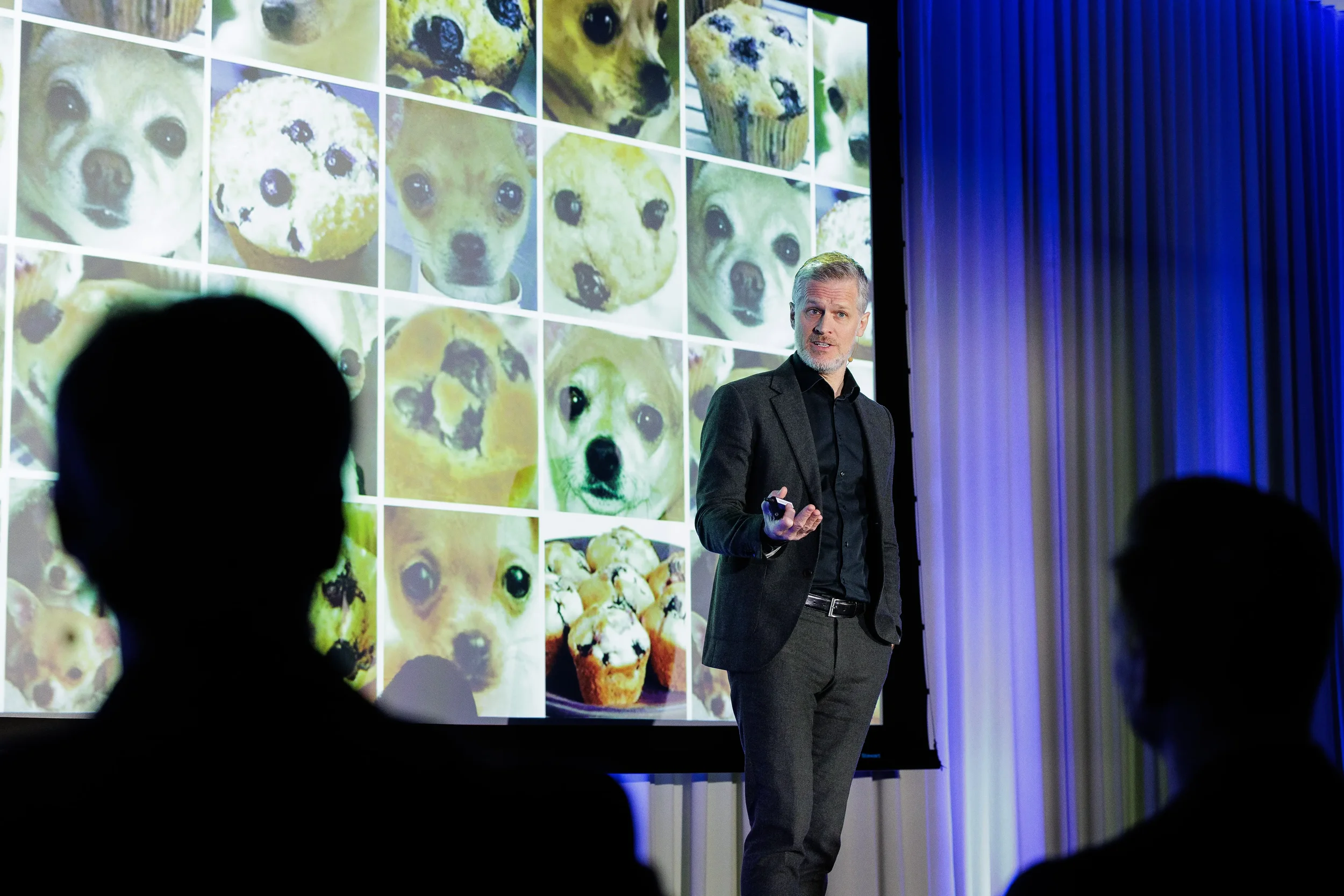Speaker gestures beside image grid slide with audience silhouettes at Orlando industry conference