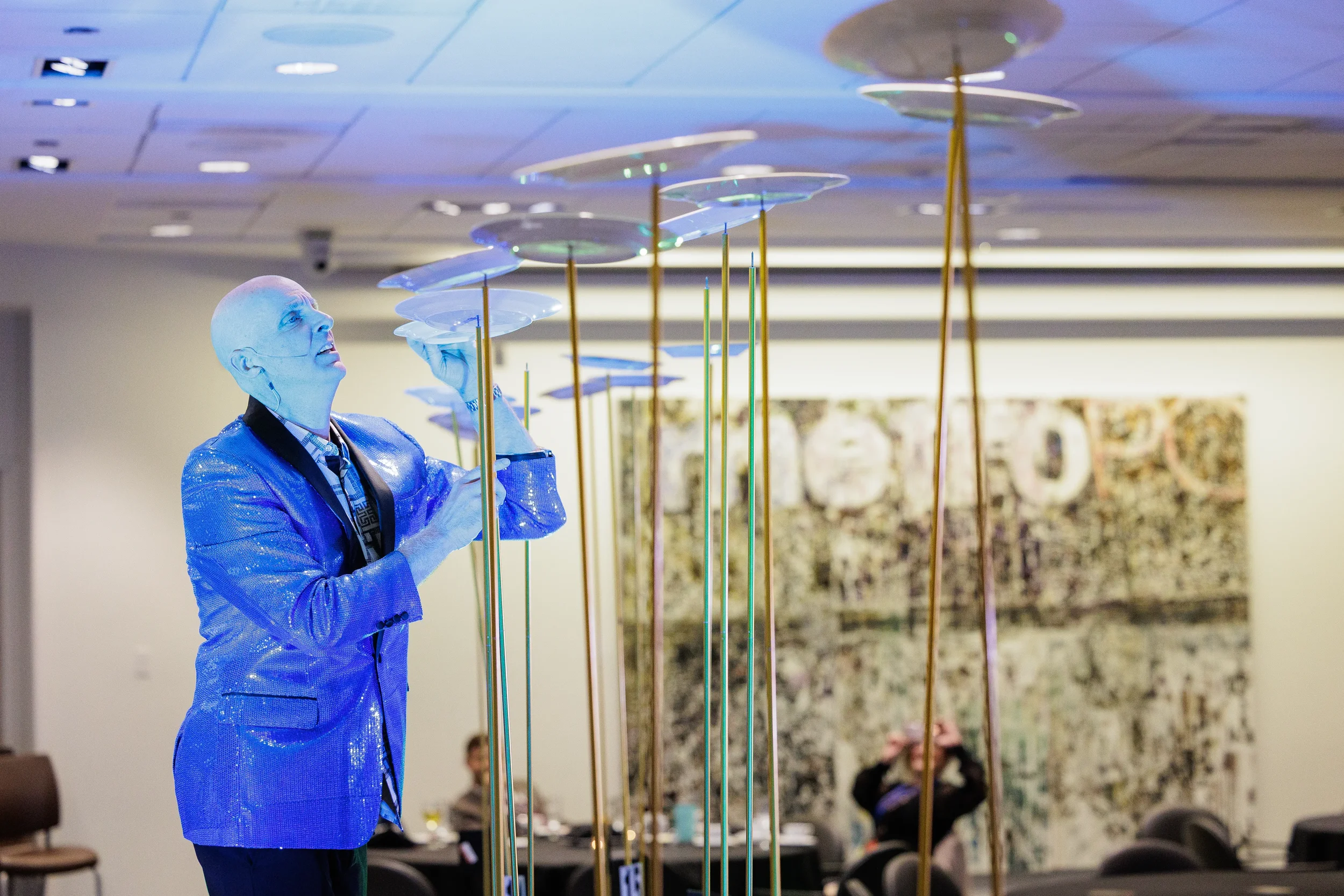 Blue costumed entertainer spins plates on tall poles during Orlando corporate conference event program