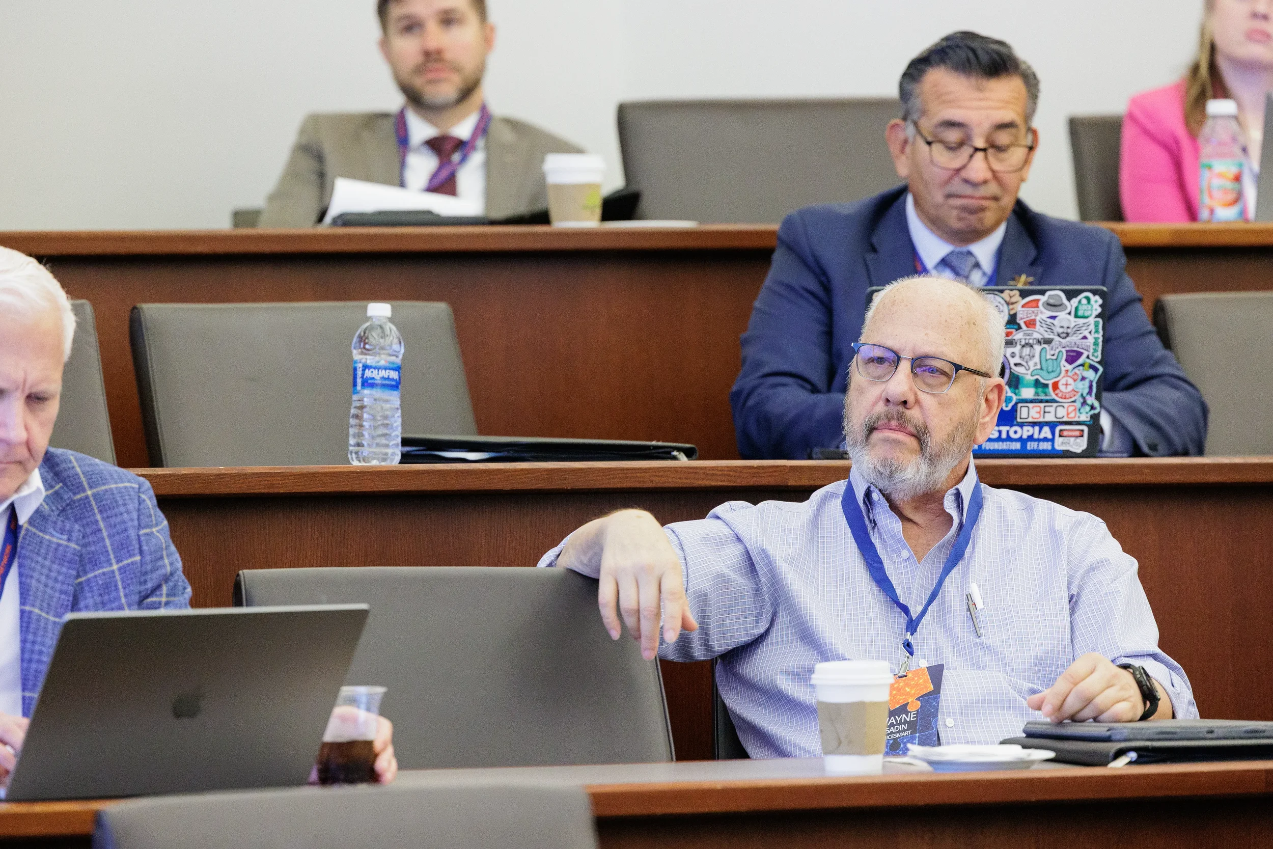 Male attendee with lanyard listens attentively during session in tiered room at Chicago corporate conference