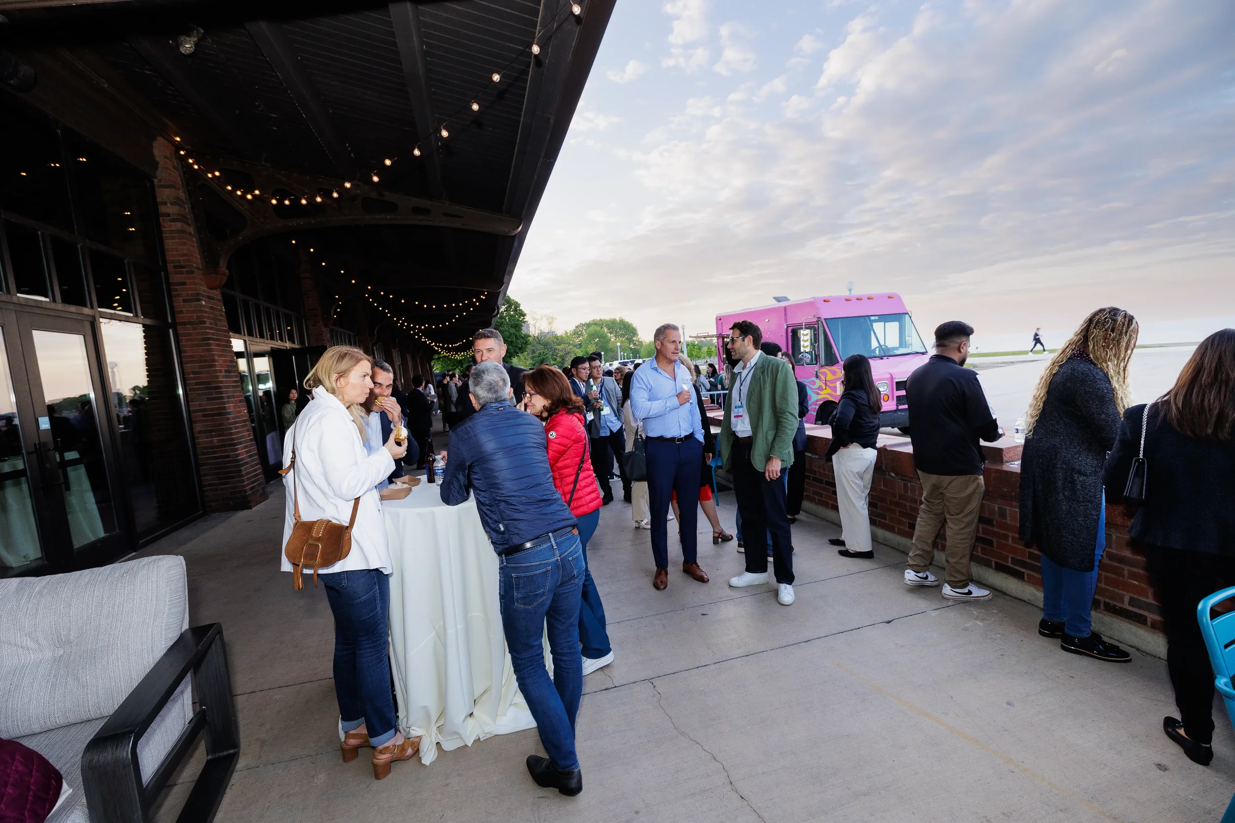 Guests network at outdoor patio reception with string lights and food truck near Chicago lakefront