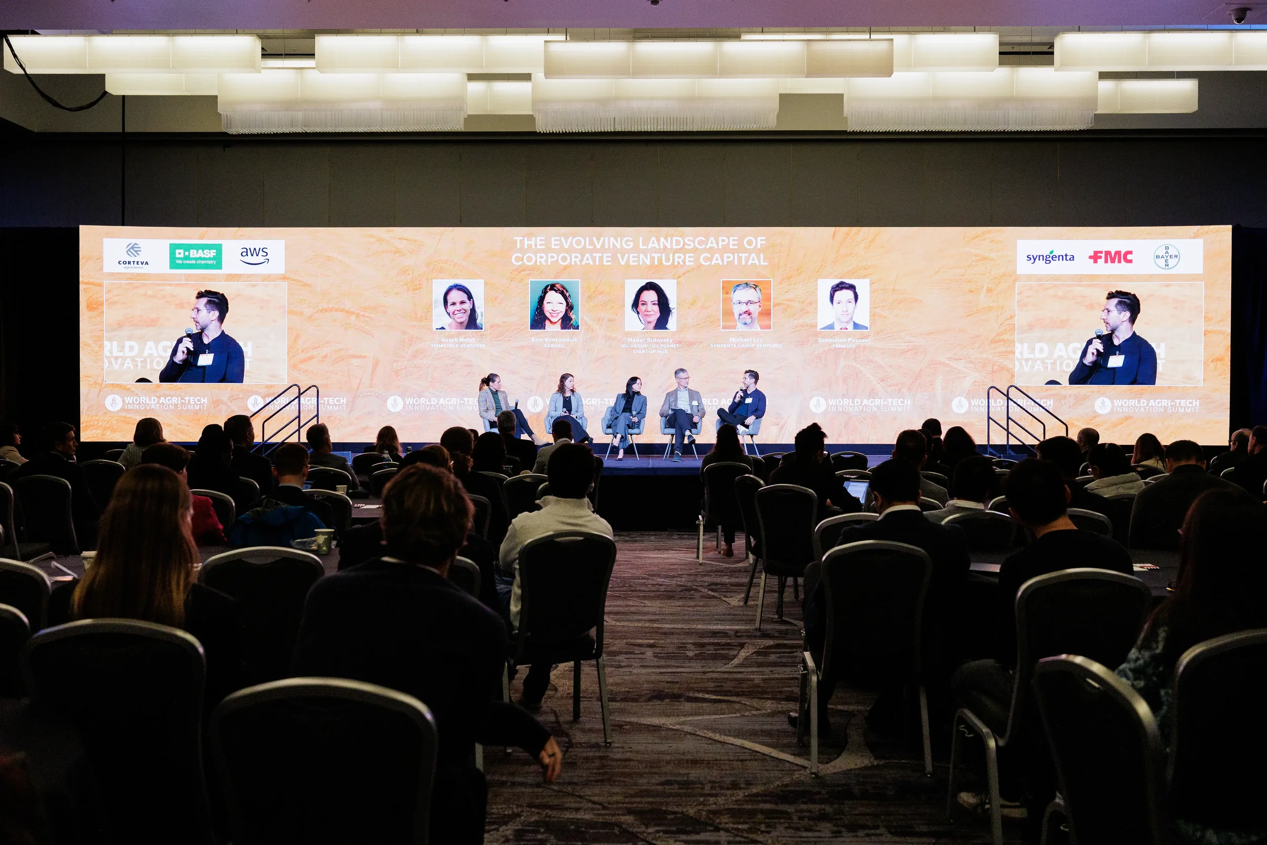 Panel of speakers on branded stage with large LED screen behind them at Chicago industry conference