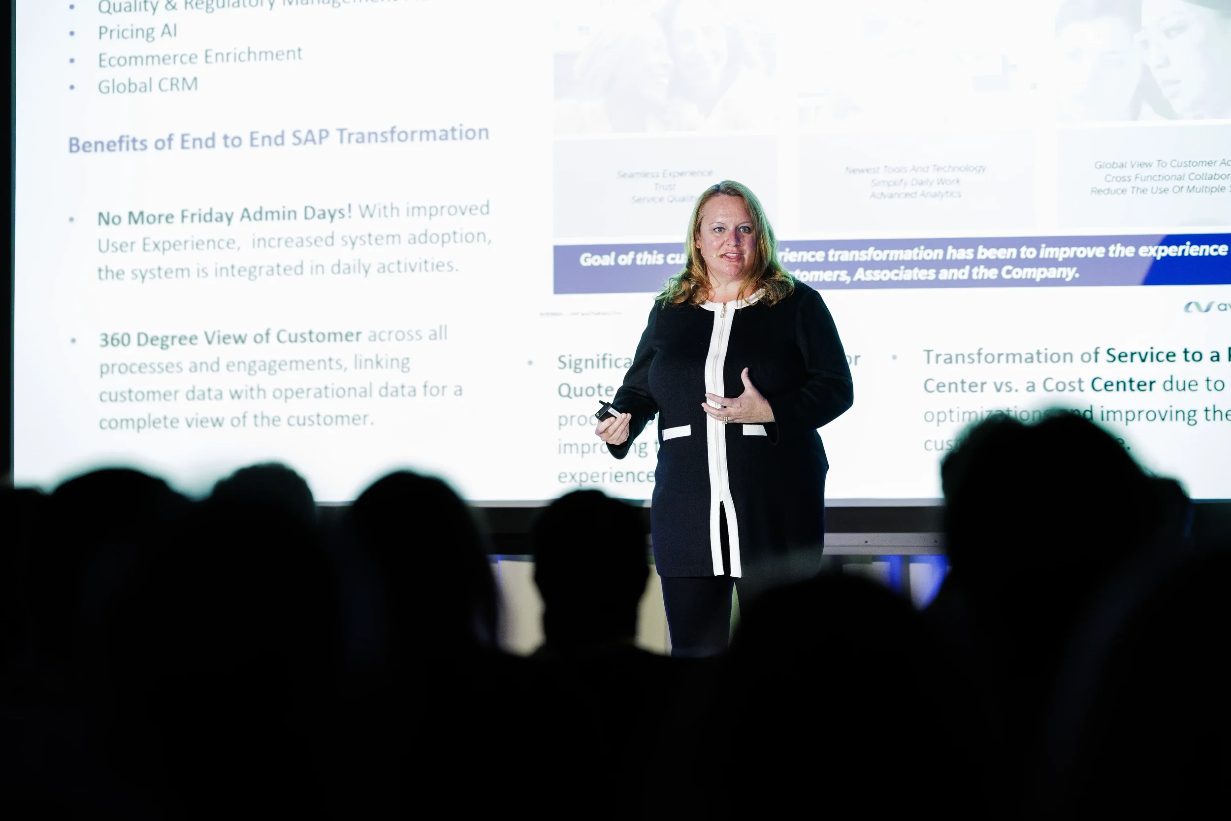 Speaker presents detailed slide to silhouetted audience on stage at Orlando corporate conference