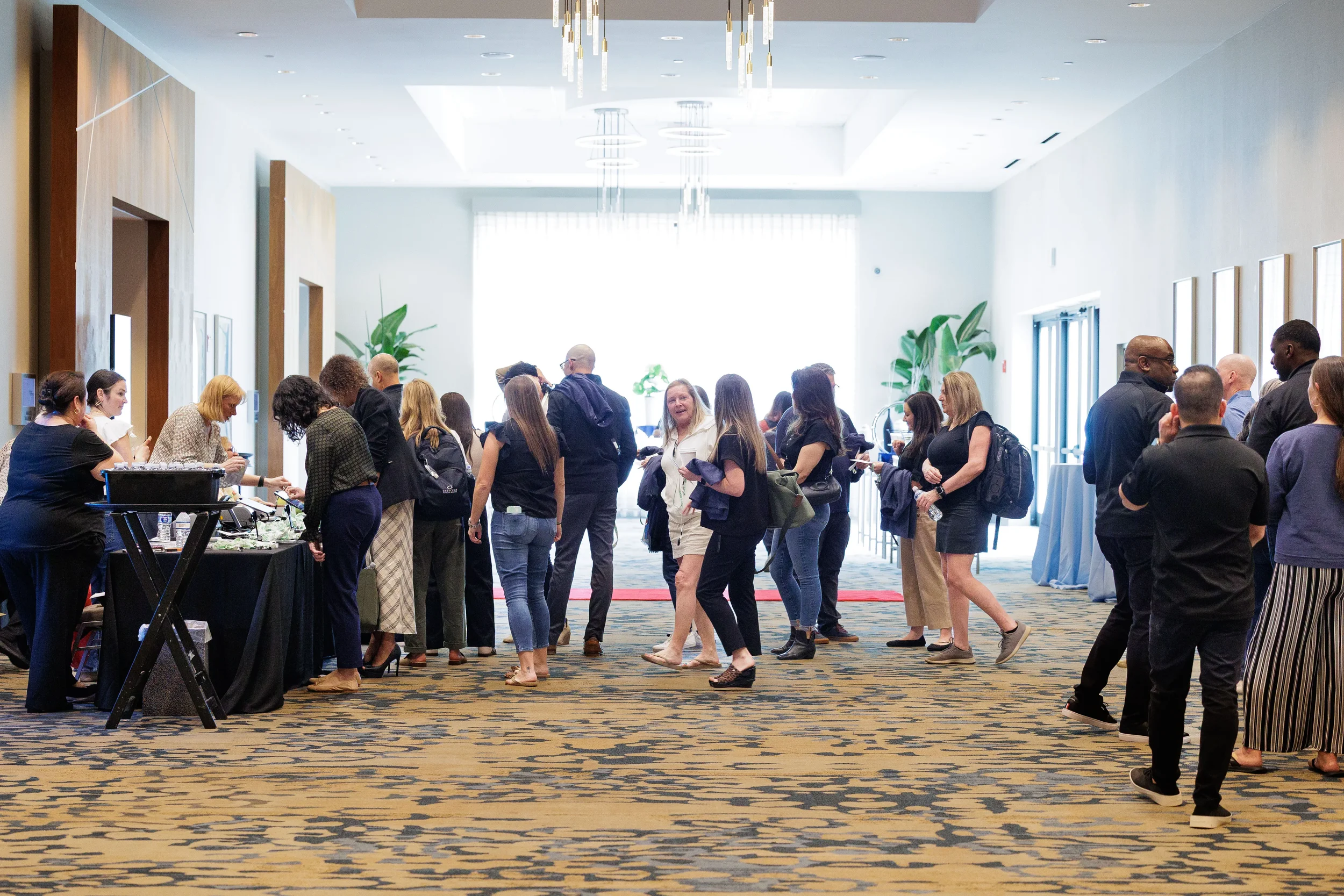 Large group of attendees queue at registration in bright hotel foyer at Orlando corporate conference