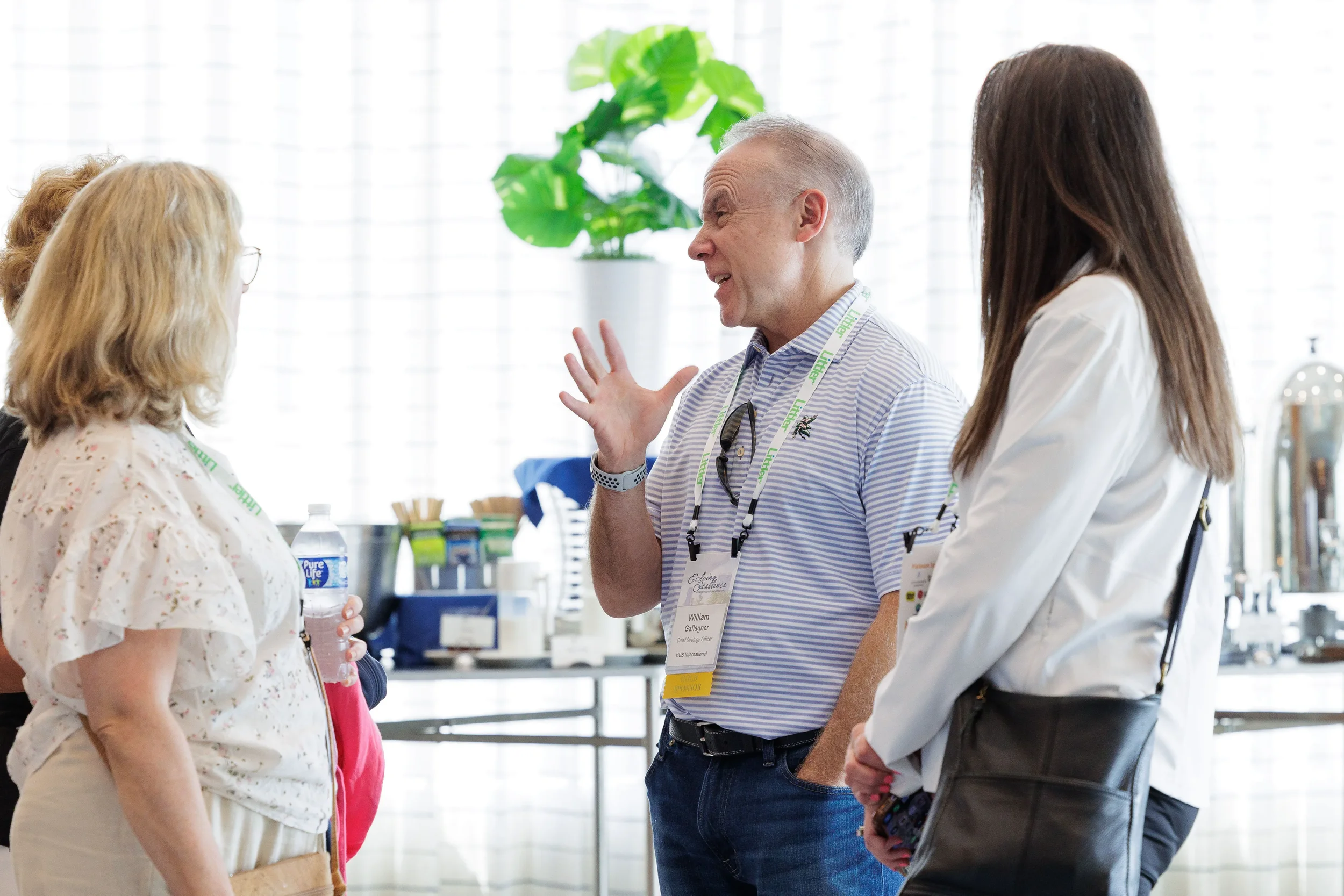 Attendee with lanyard gestures animatedly while speaking to two others at Chicago corporate conference reception