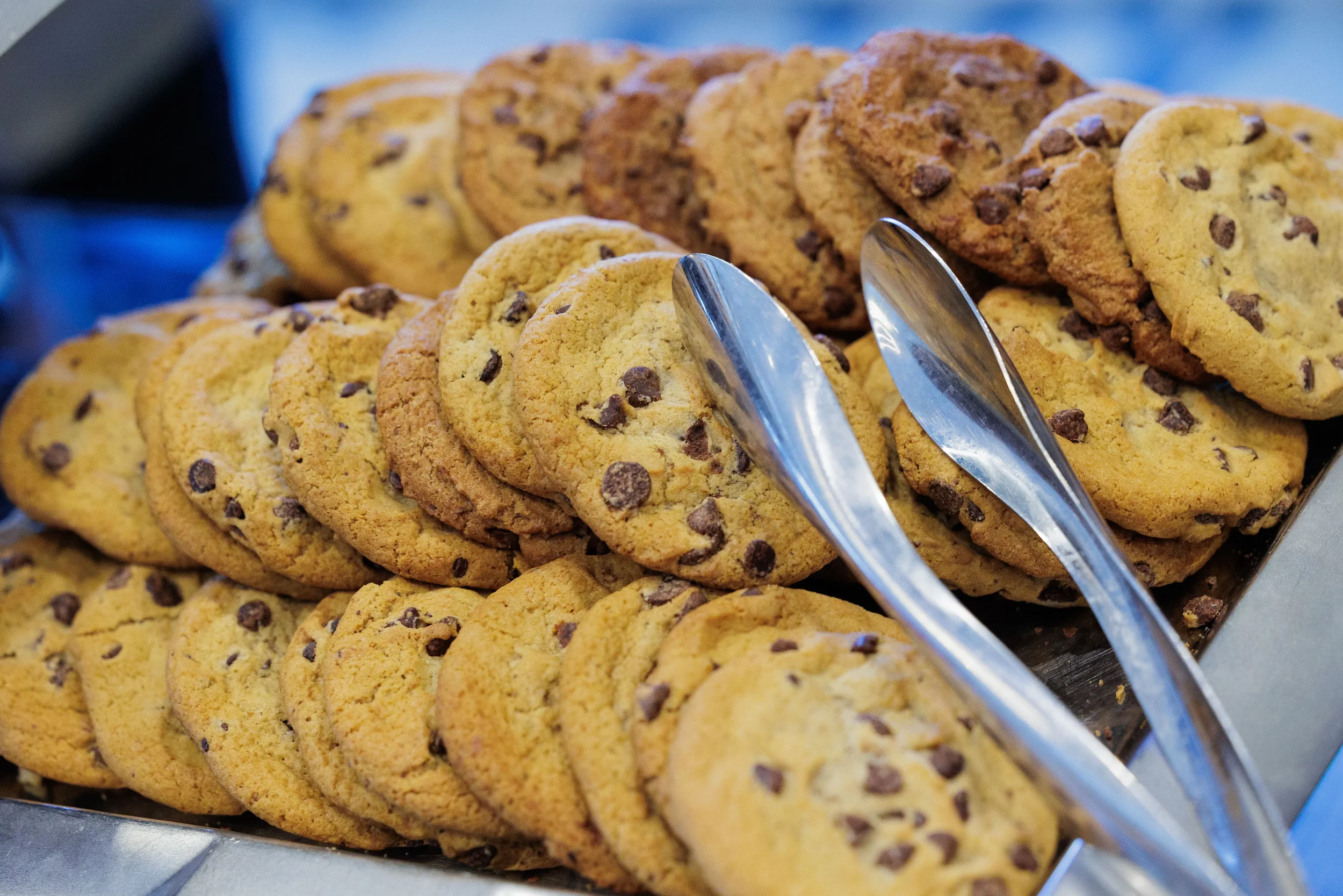 Close-up of chocolate chip cookies with tongs on catering display at Chicago corporate conference