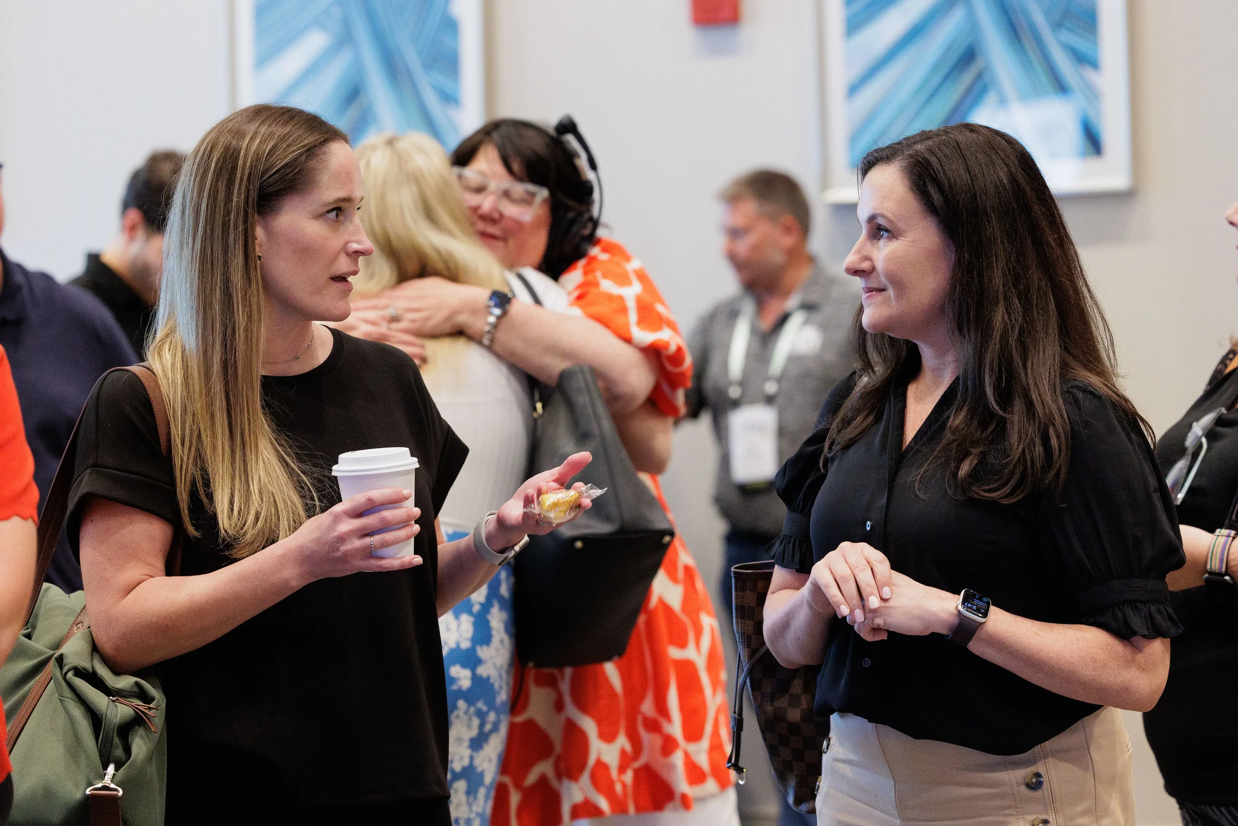 Two female attendees chat over coffee during networking break at Orlando corporate conference