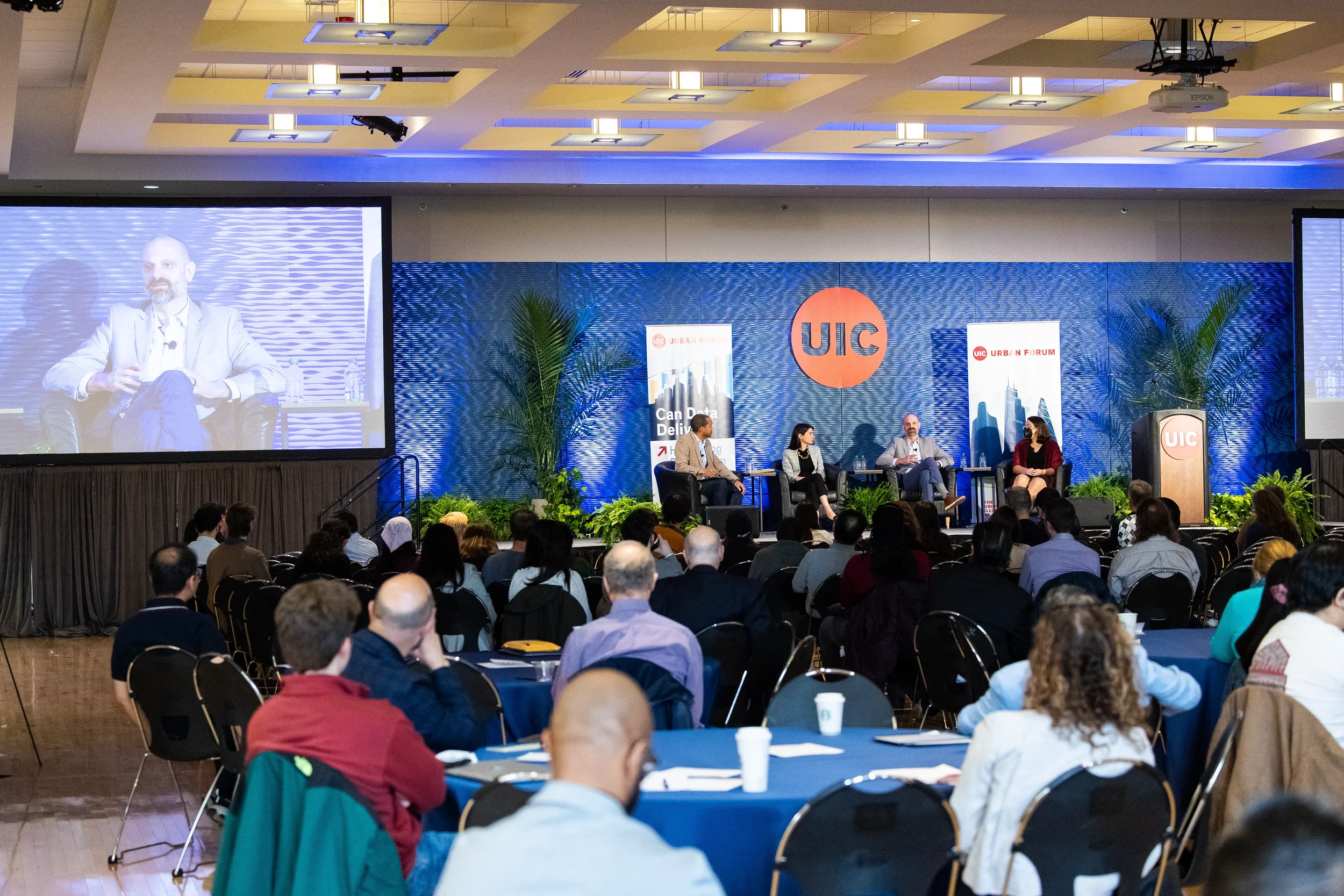 Wide view of four panelists on stage with seated audience at Orlando industry conference
