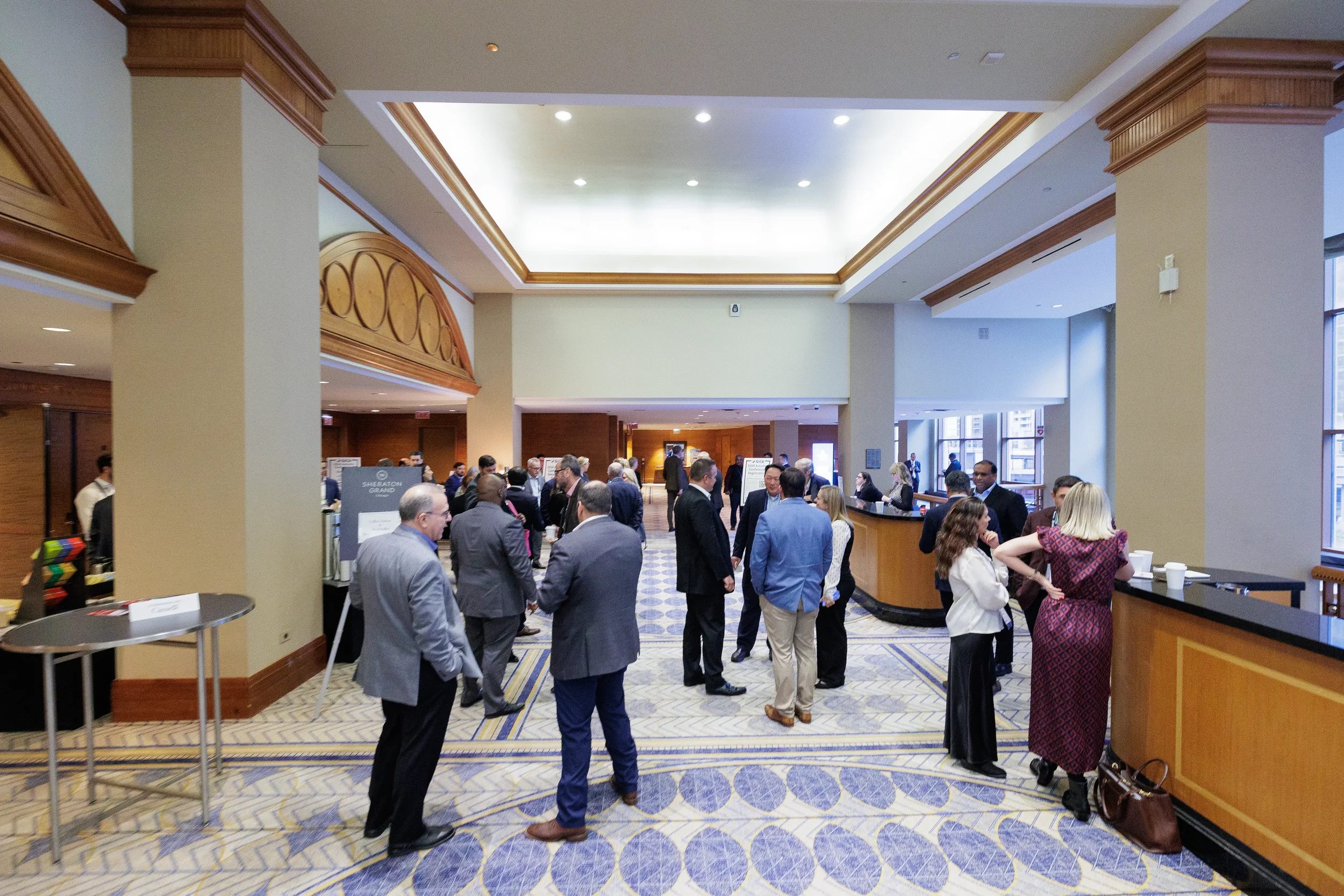 Business professionals networking in Orlando in a hotel lobby with high ceilings, decorative pillars, and patterned carpeting