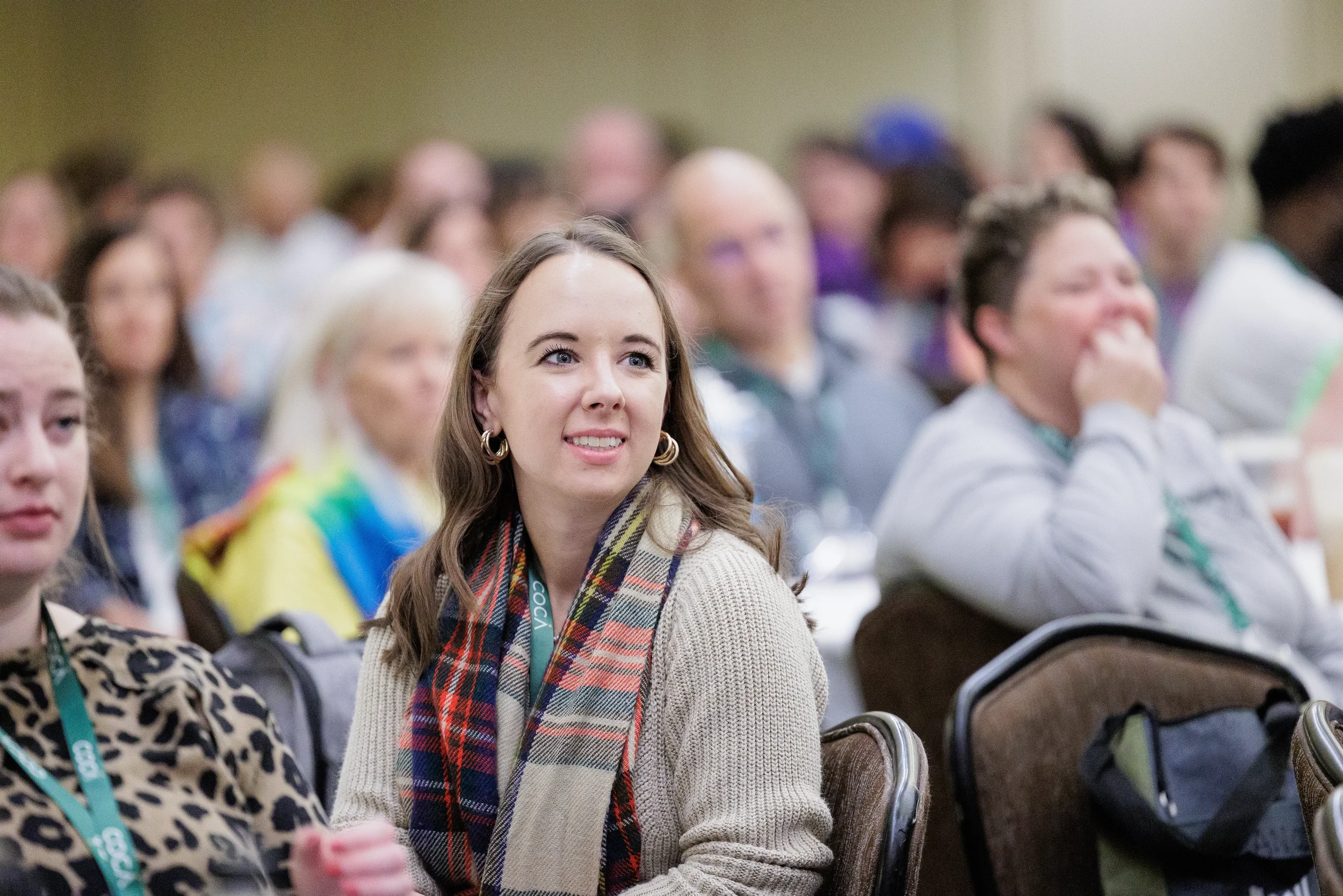 Attendee wearing conference lanyard watches presentation intently in audience at Chicago nonprofit conference