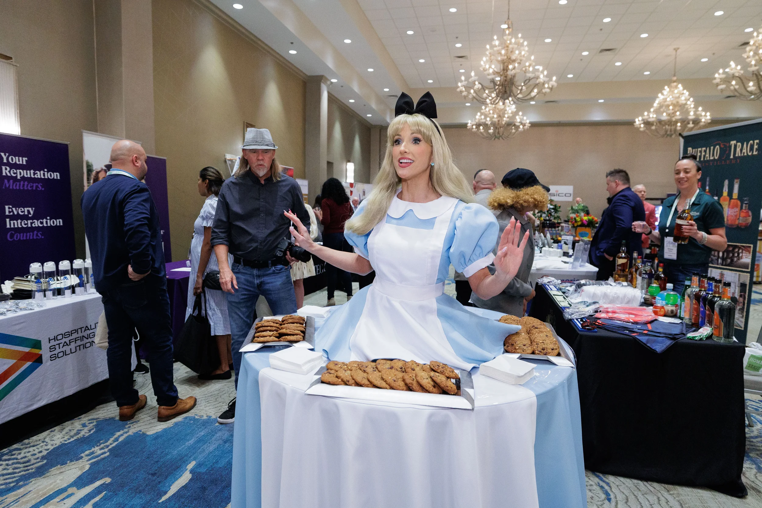 Costumed character poses with cookie display at trade show booth in chandelier ballroom at Chicago corporate event