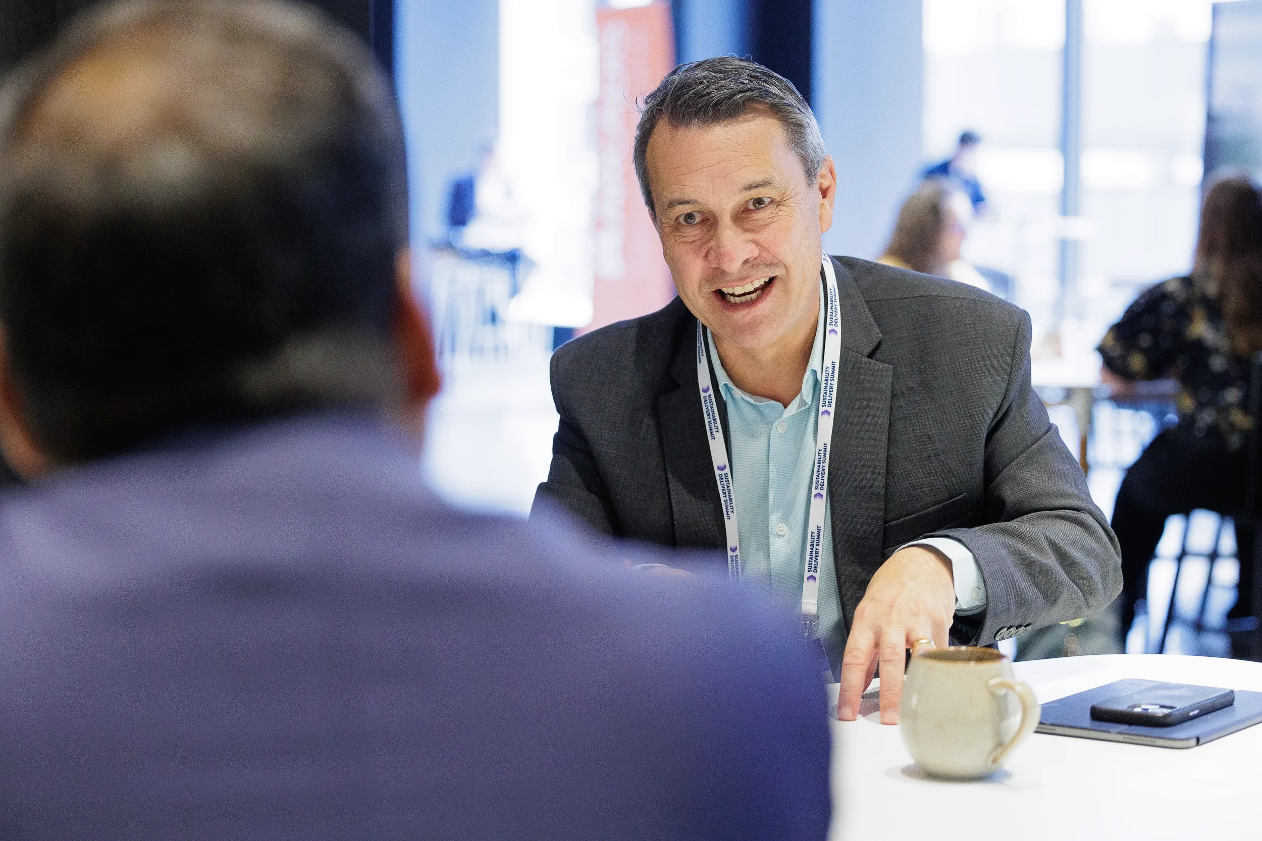 Attendee smiles during seated conversation at table during Orlando corporate conference