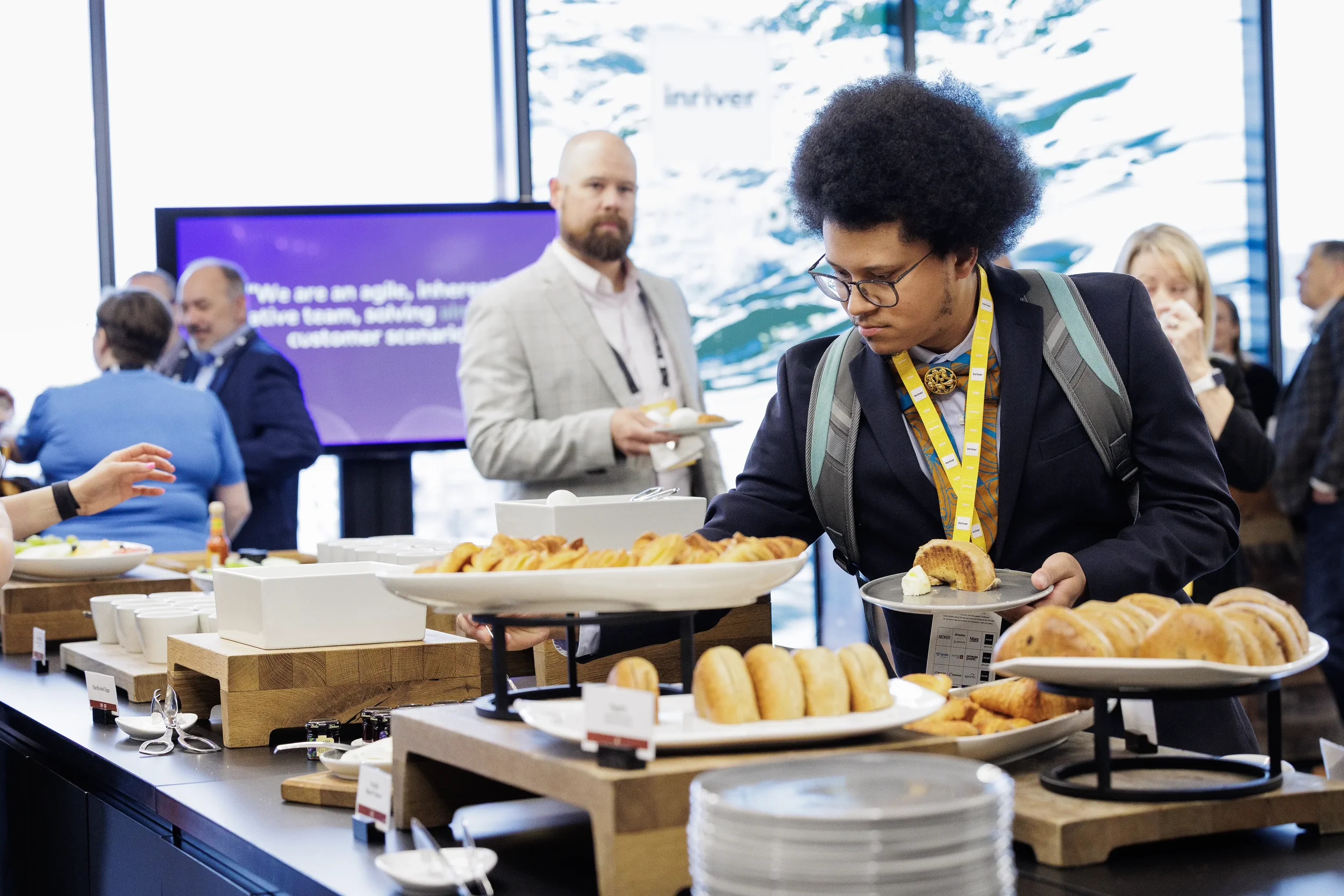 Attendee with lanyard selects pastry from breakfast buffet during networking break at Chicago corporate event