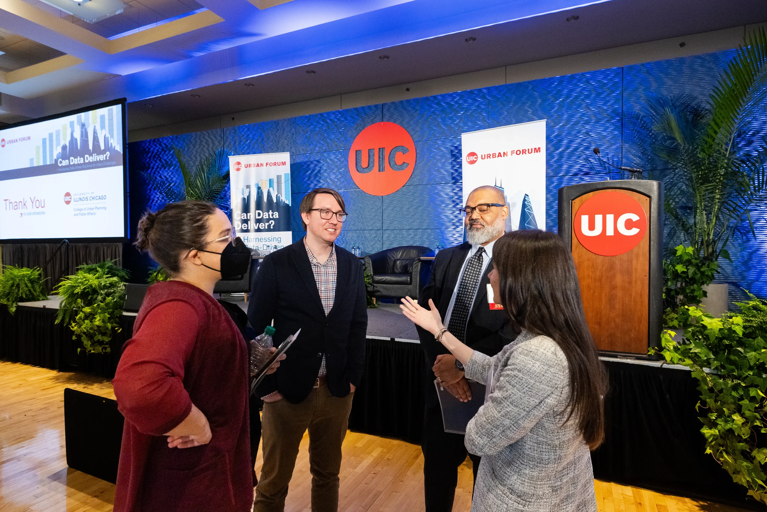 Four attendees converse in front of branded stage after session at Chicago industry conference