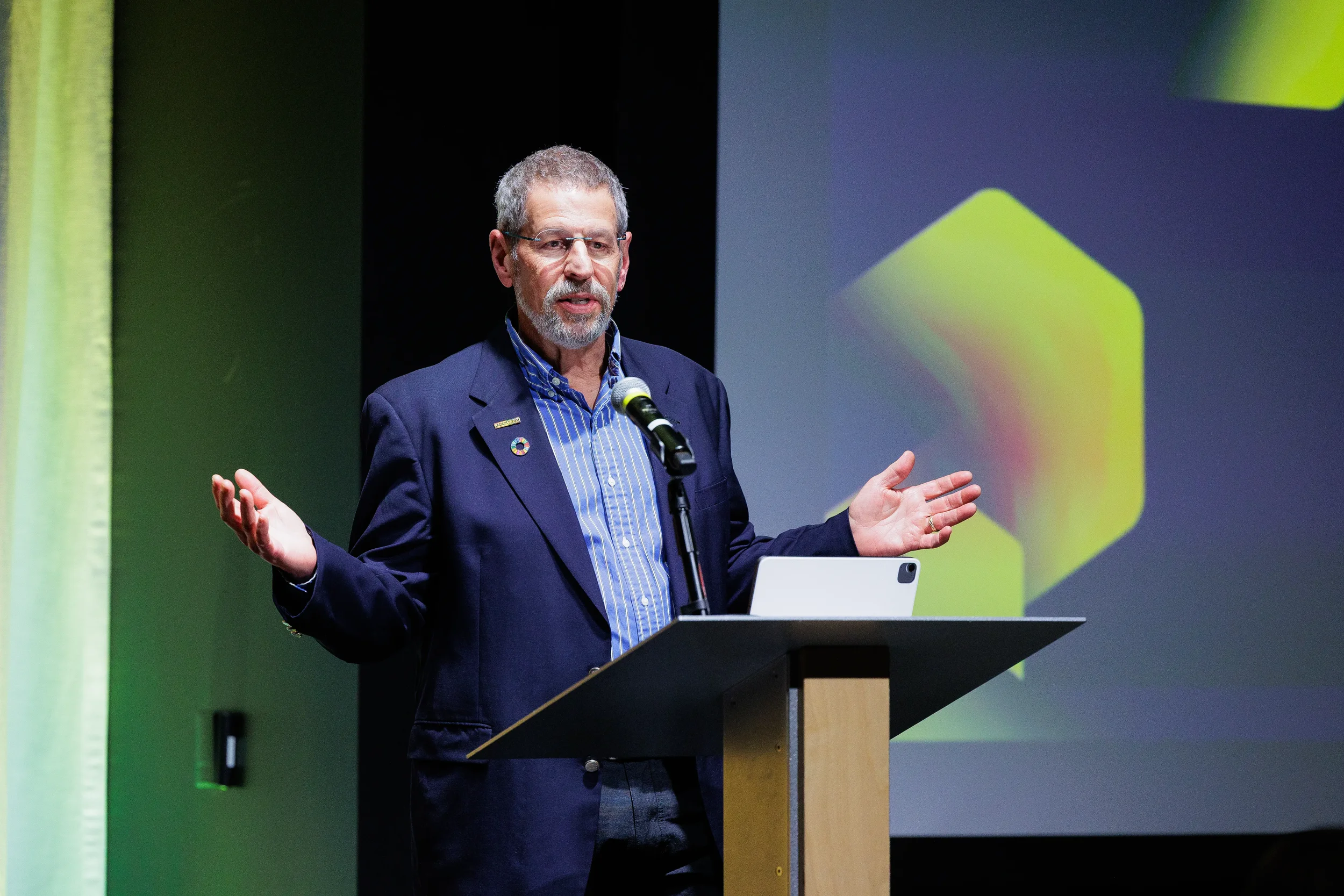 Speaker gestures from podium with tablet during Chicago industry conference presentation