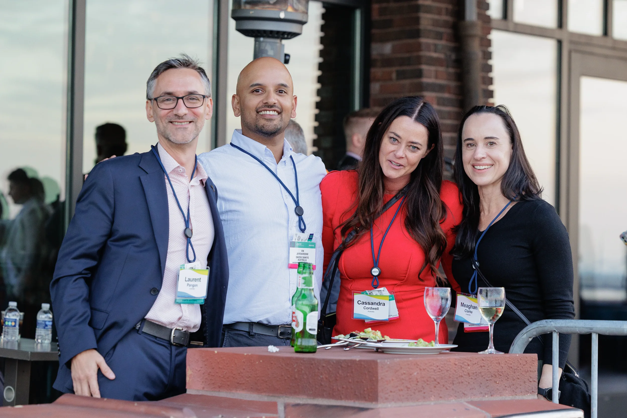 Four smiling colleagues with lanyards pose together at outdoor networking reception in Orlando