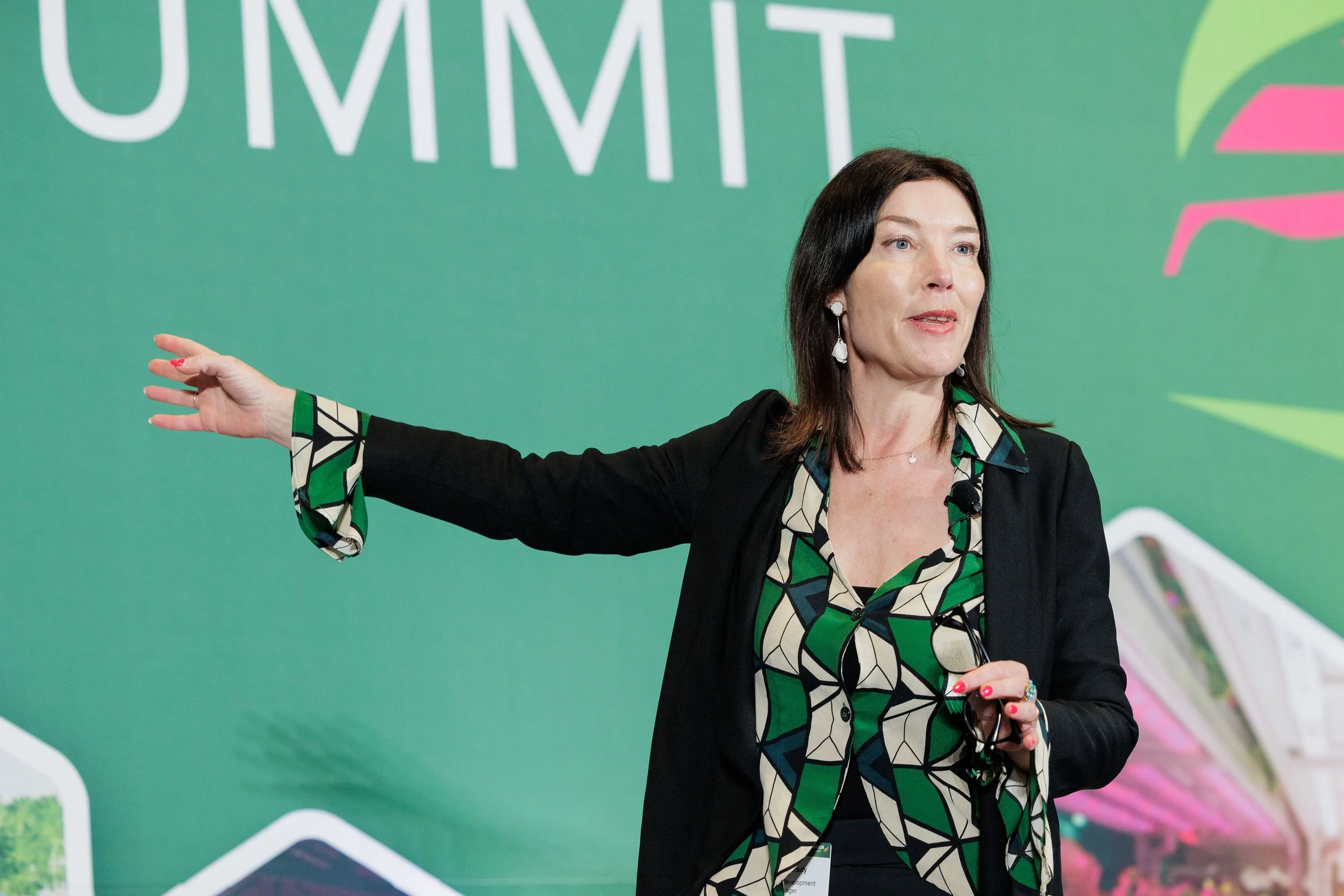 Keynote speaker gesturing expressively on stage while presenting at professional industry summit in Orlando