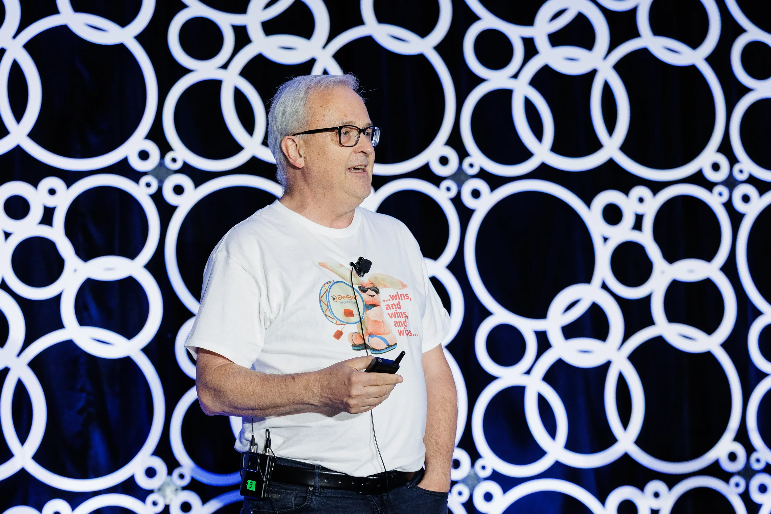 Speaker addresses audience on stage with illuminated circular backdrop at Chicago conference
