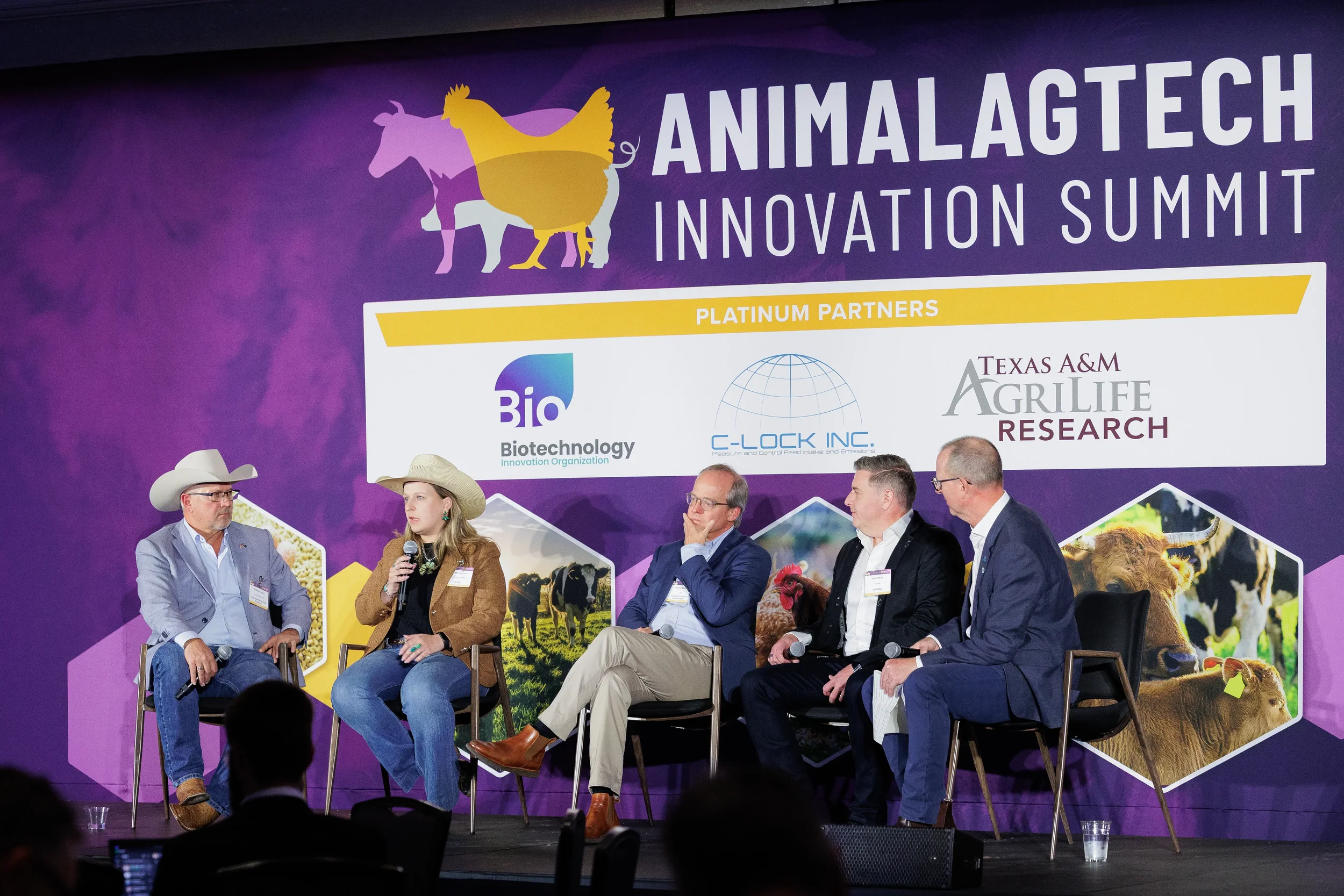 Five panelists seated on stage before full event banner at Orlando industry conference