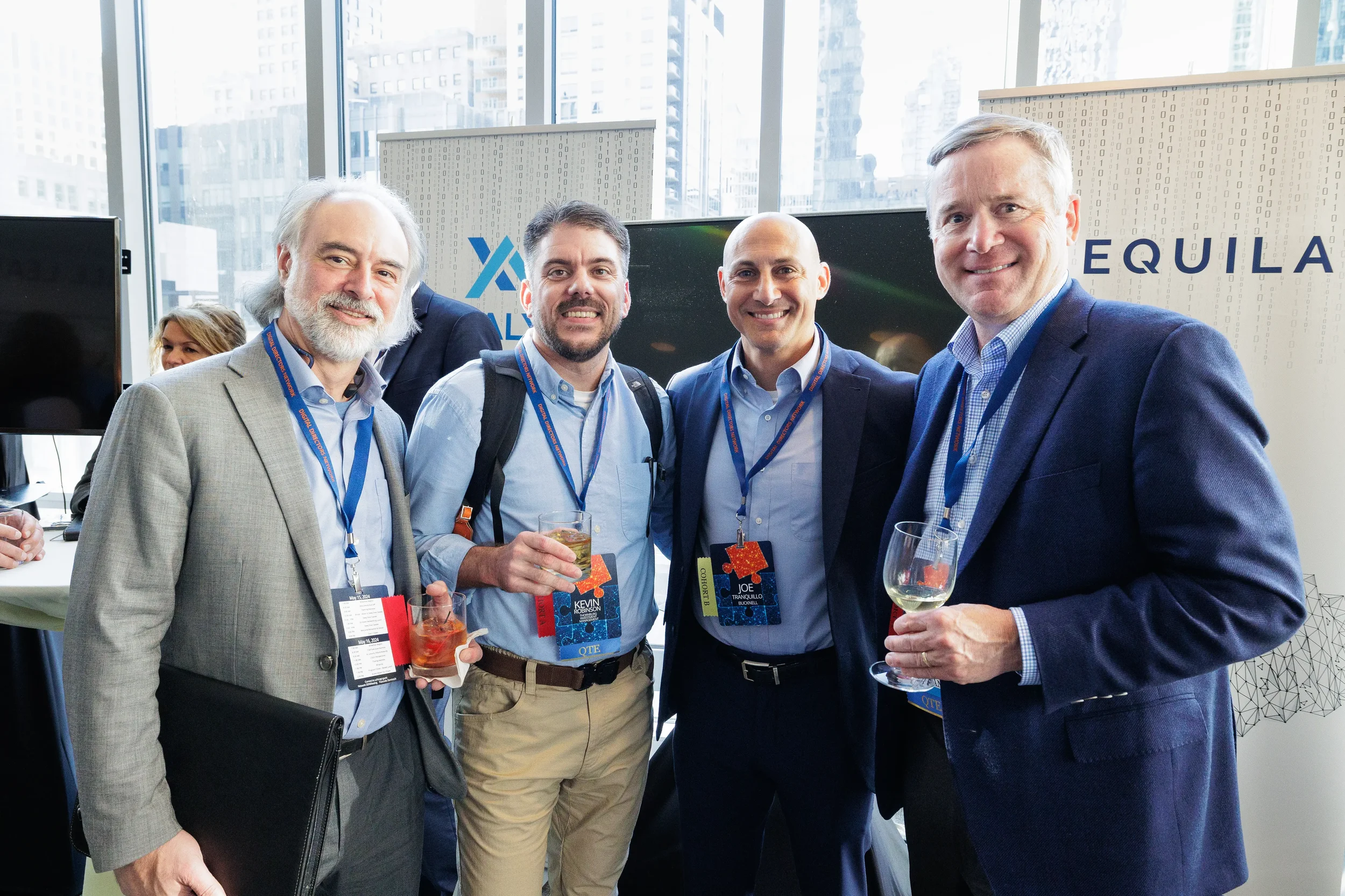 Four male attendees with lanyards smile and hold drinks during Chicago corporate conference networking reception