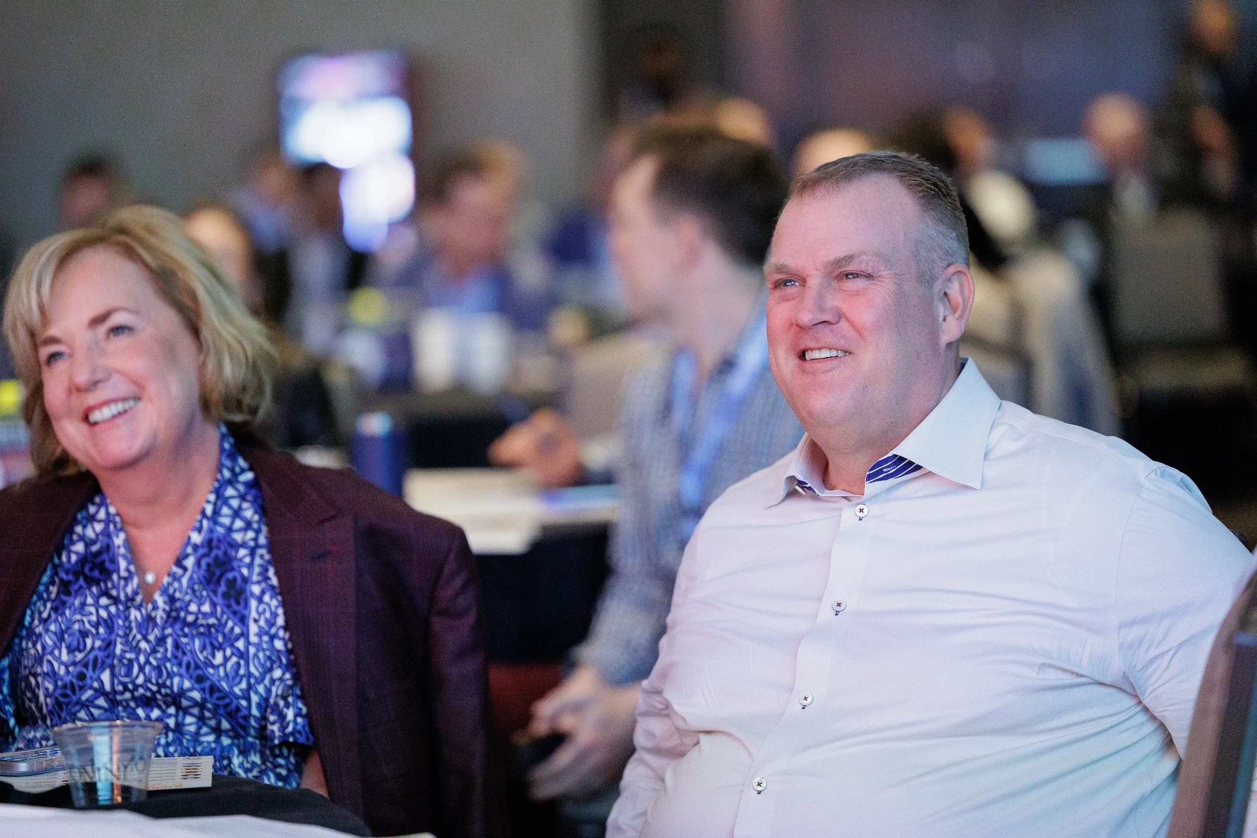 Two attendees laugh together while seated at table during session at Chicago corporate conference event