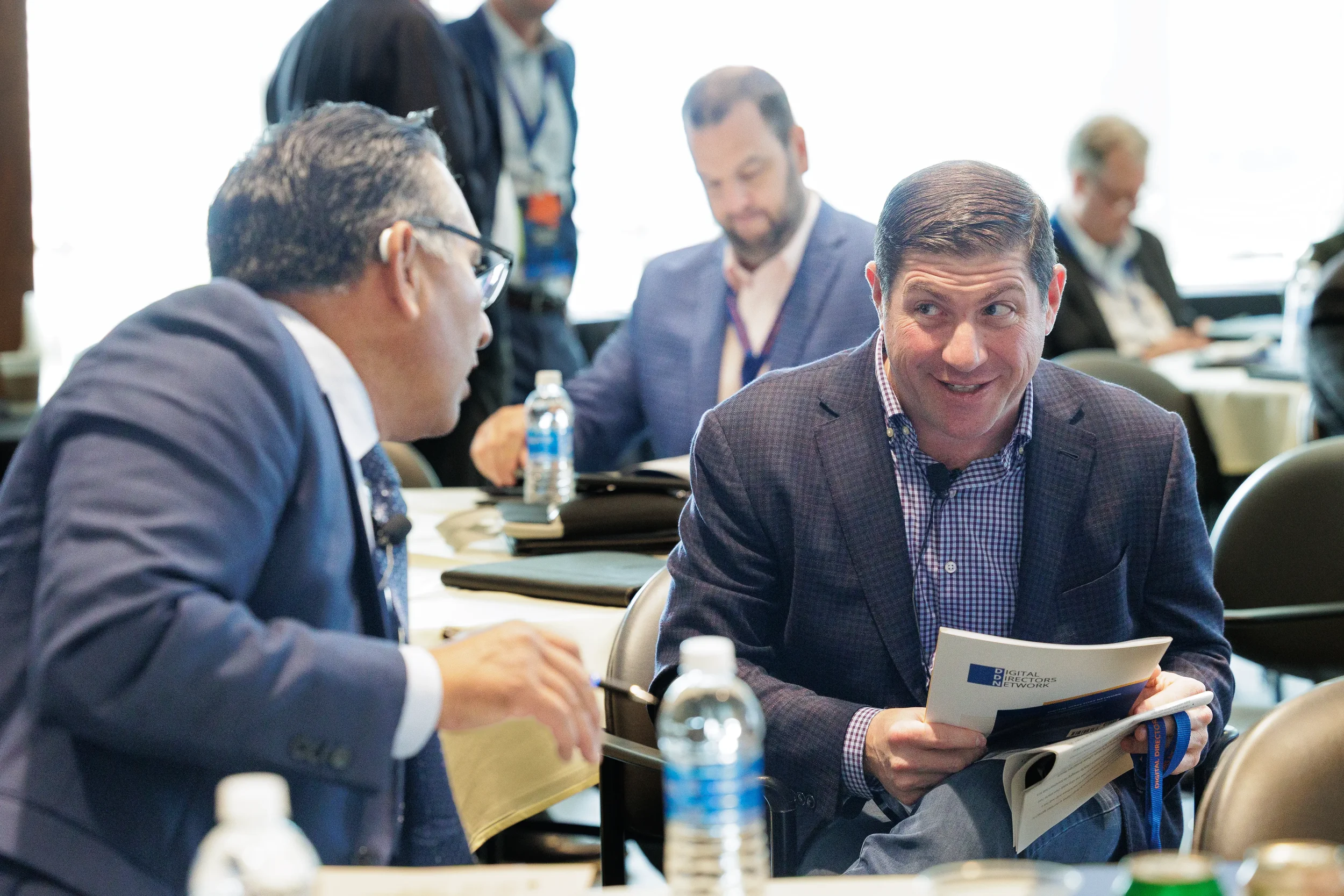 Two attendees converse over conference materials at table during Orlando industry conference networking