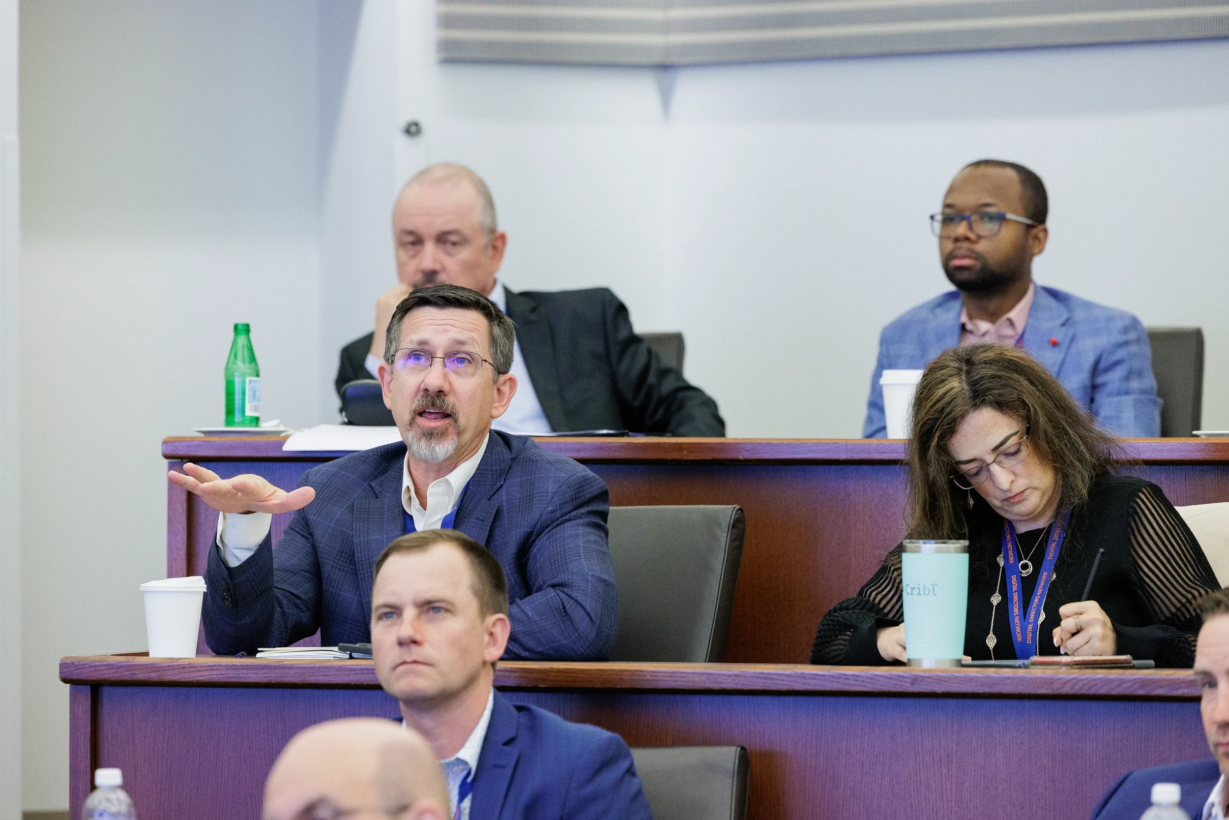 Male attendee gestures while asking question during session in tiered room at Orlando corporate conference