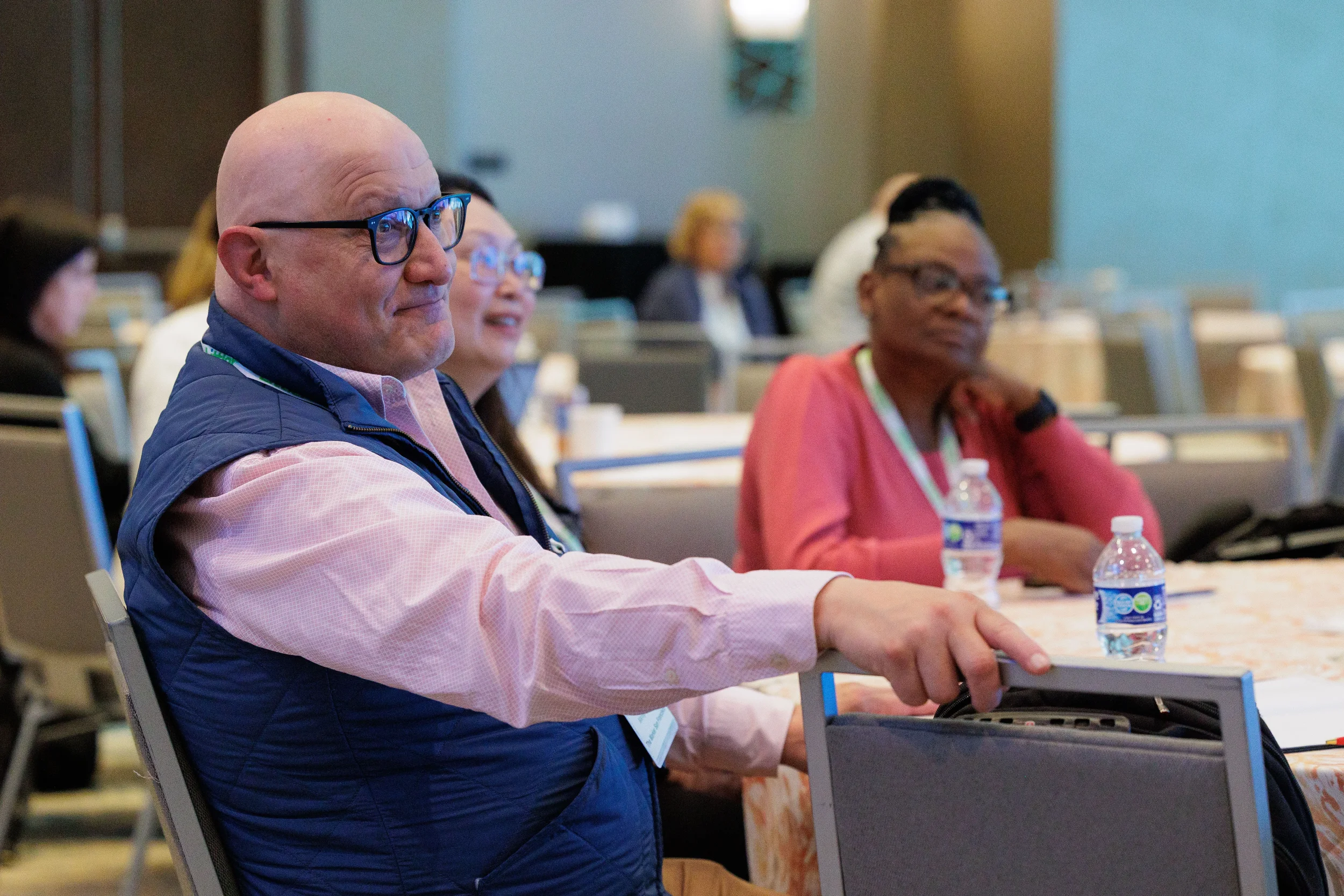 Attendees with lanyards seated at round tables during general session at Chicago corporate conference
